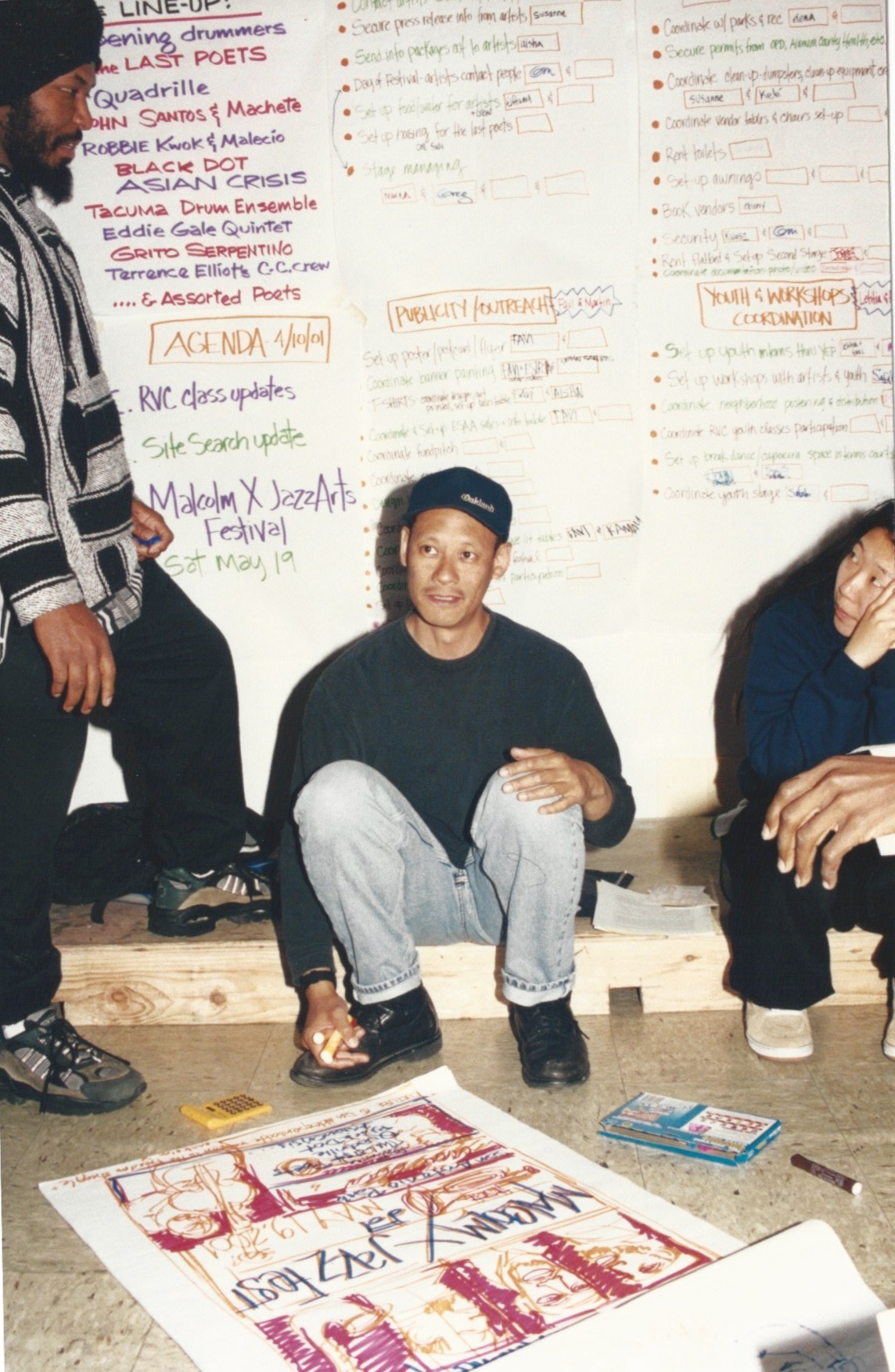 A man sitting in front of a white board with writing on it.