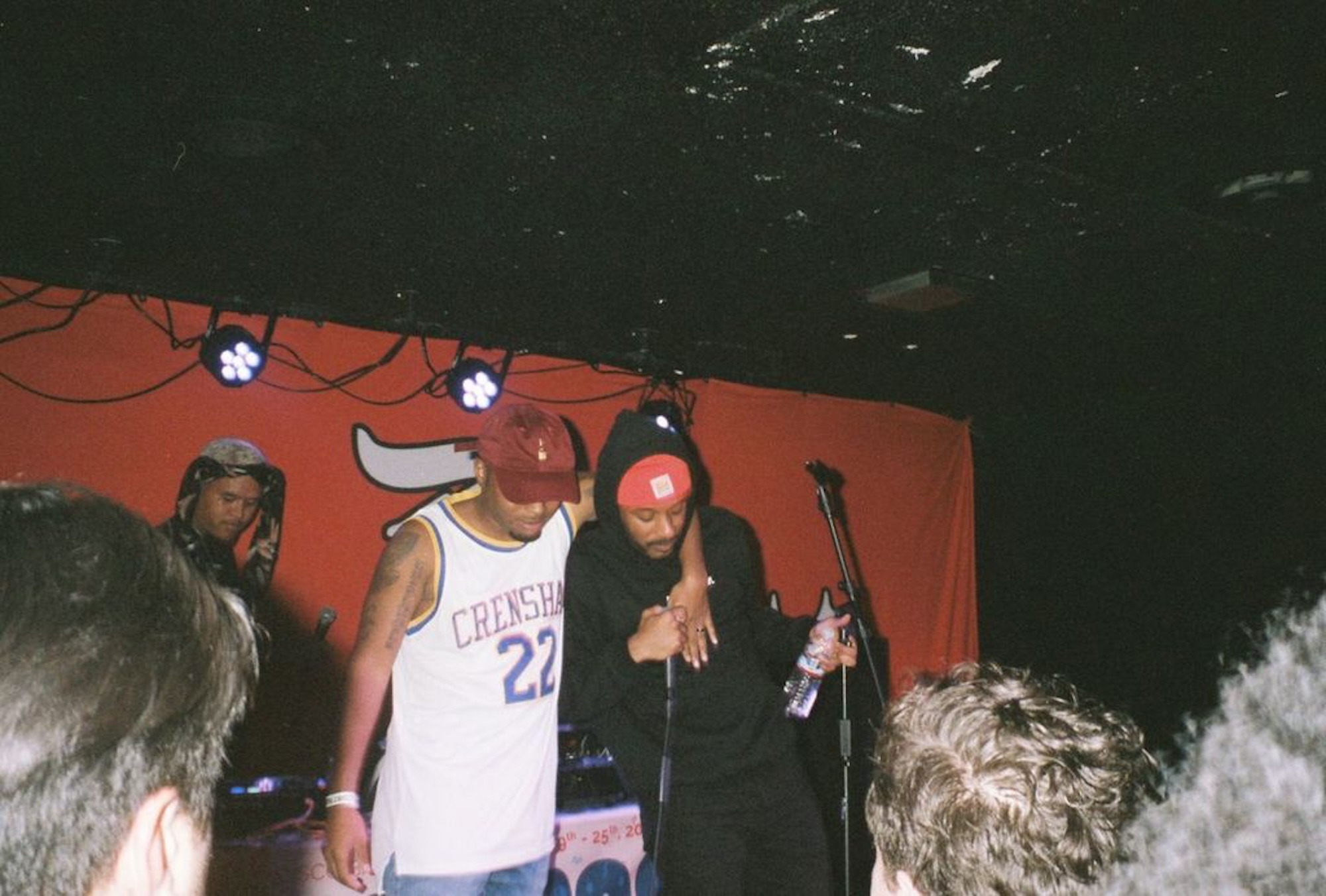 Two men share an embrace while on stage during a hip-hop performance. 