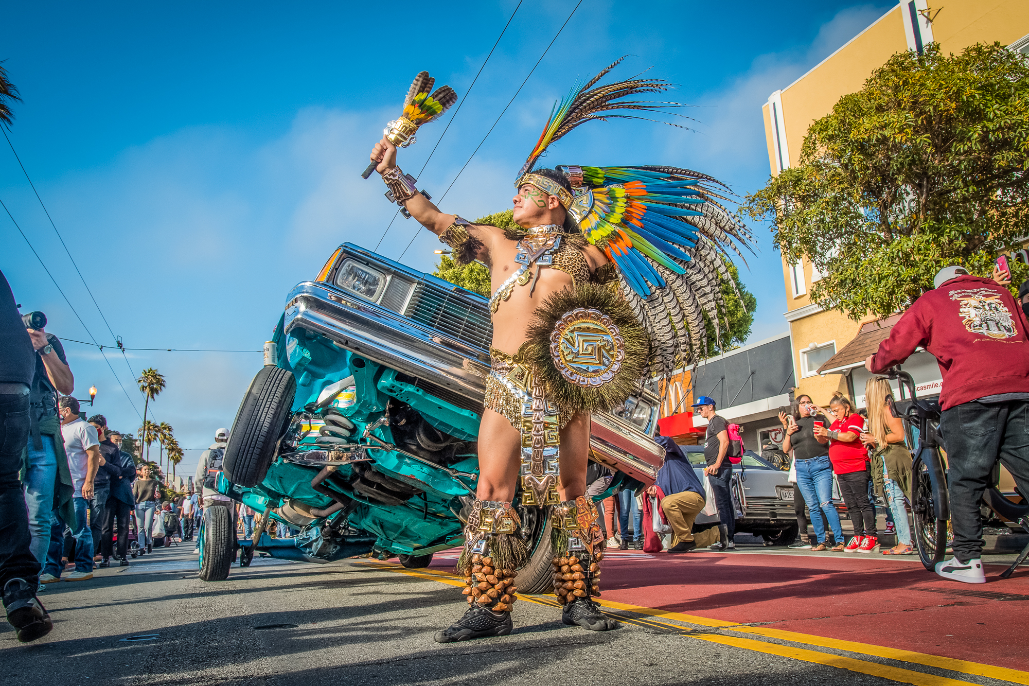 Danza Azteca performer in front of hopping lowrider