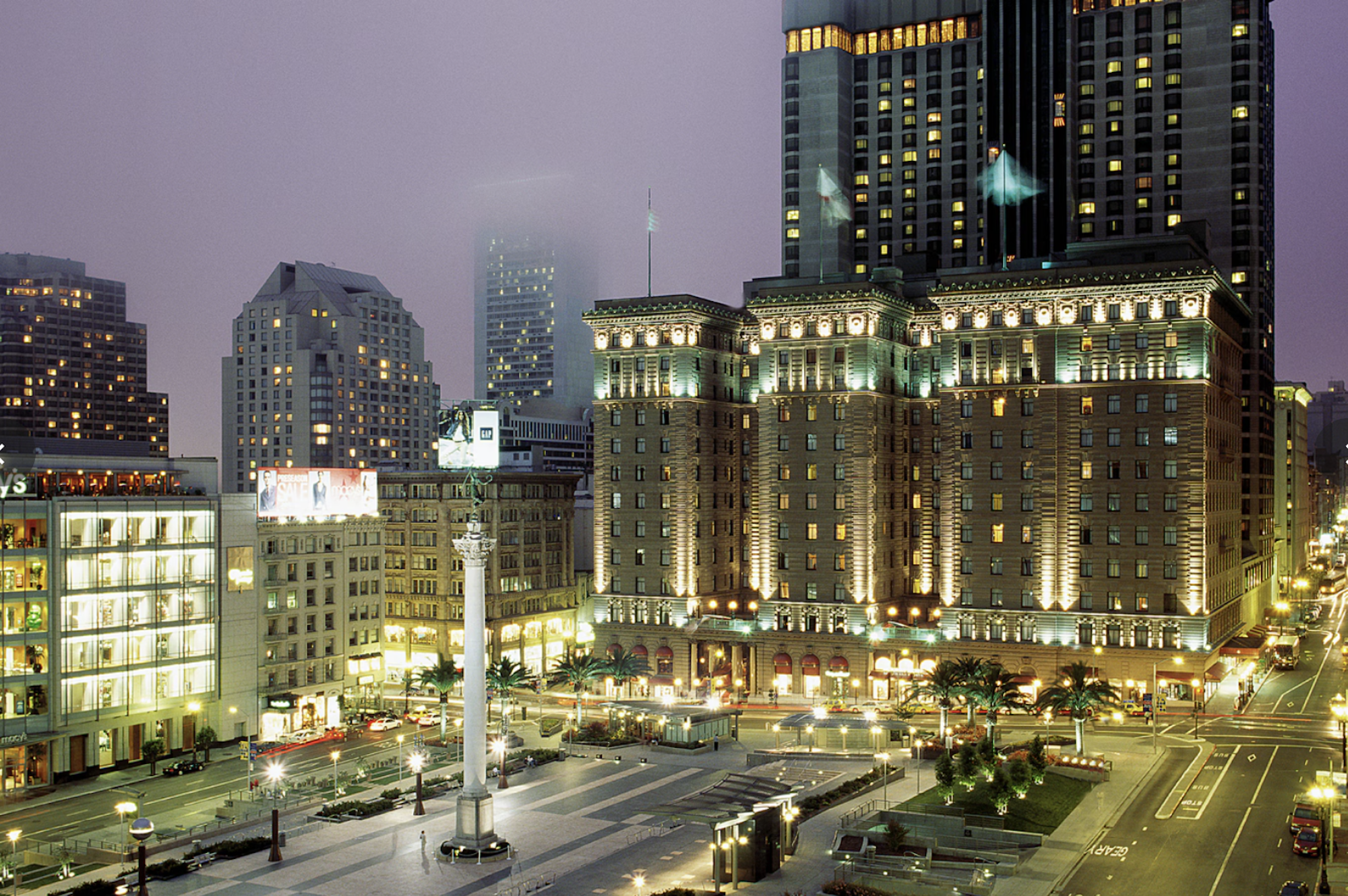 A large, grand hotel lit up at night, overlooking San Francisco's Union Square.