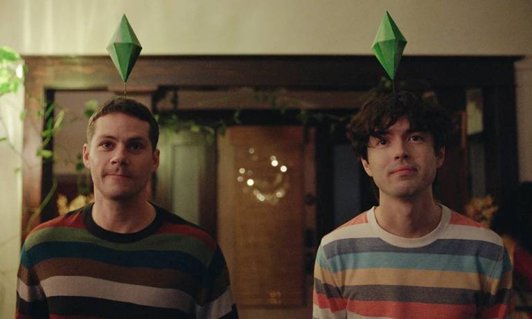 Two men wearing colorful striped sweaters look at the camera.