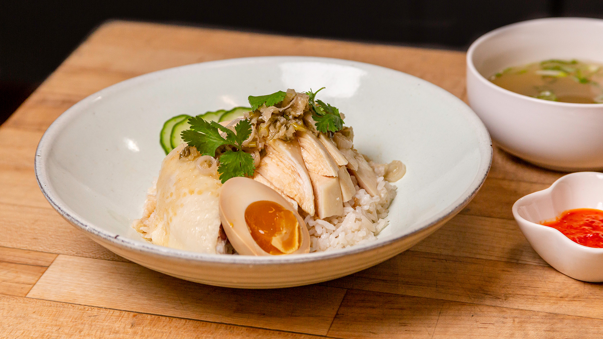 Plate of poached chicken over rice, with a bowl of broth on the side.