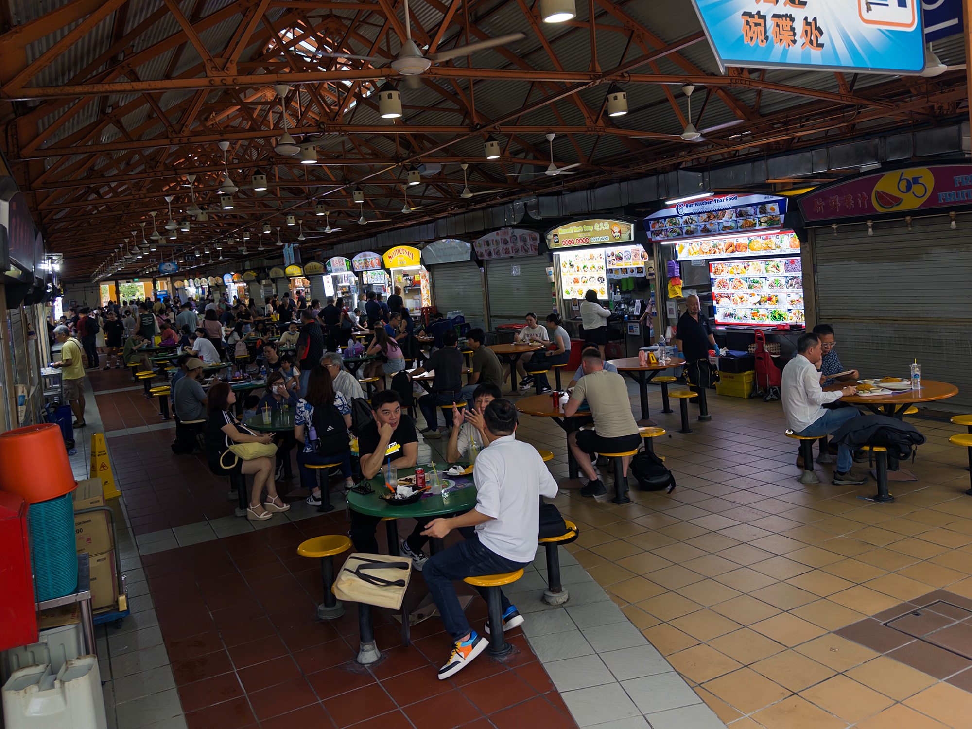 A crowd of diners seated inside a Singaporean hawker center.