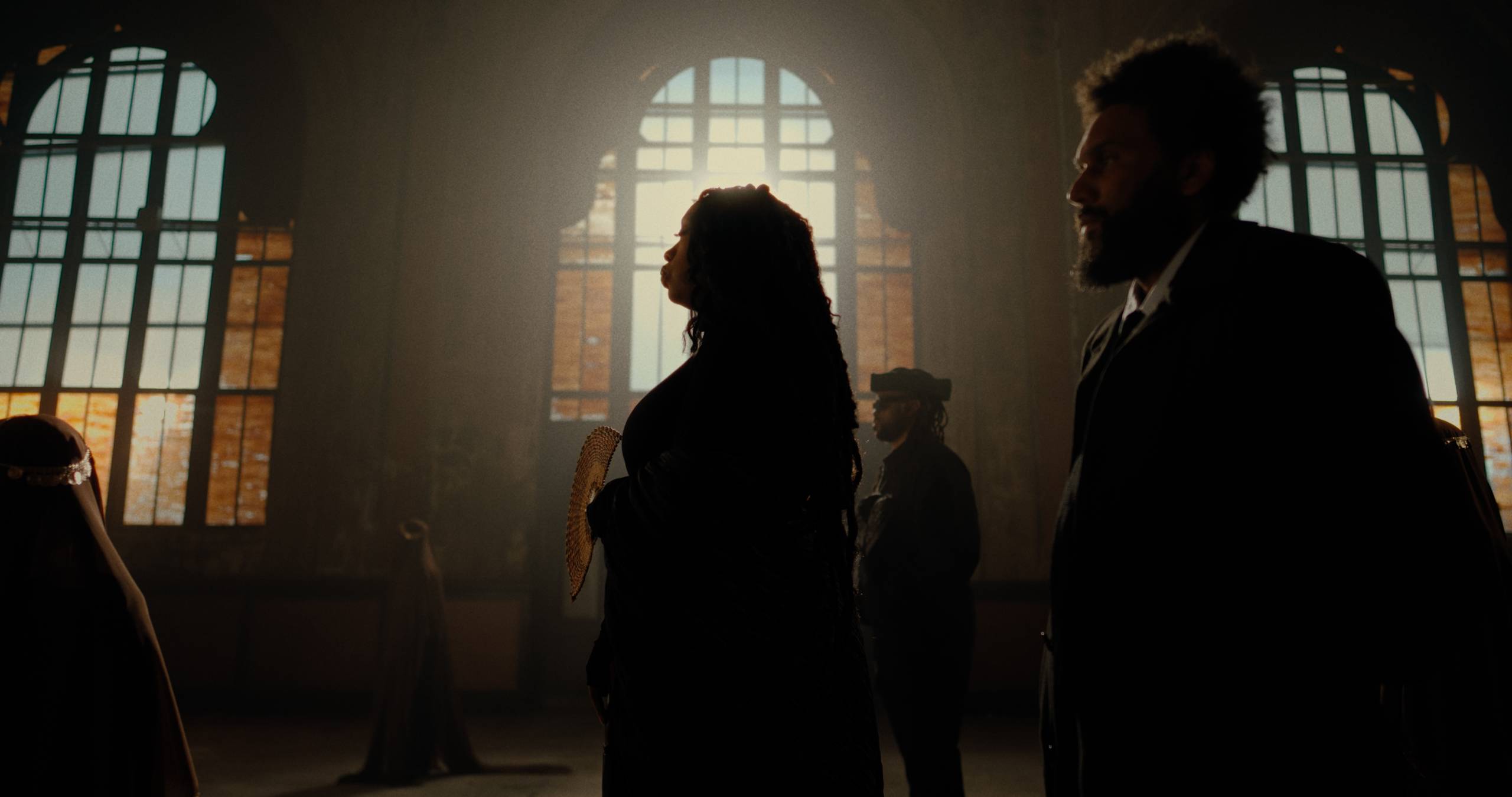 A silhouette image of three people standing in an old train station.