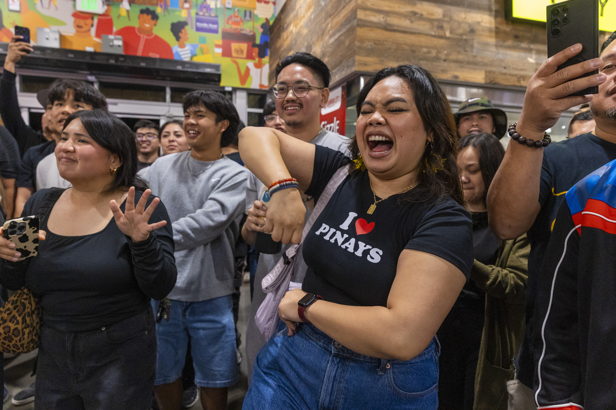 A crowd of Filipino Americans dancing and singing inside a grocery store.