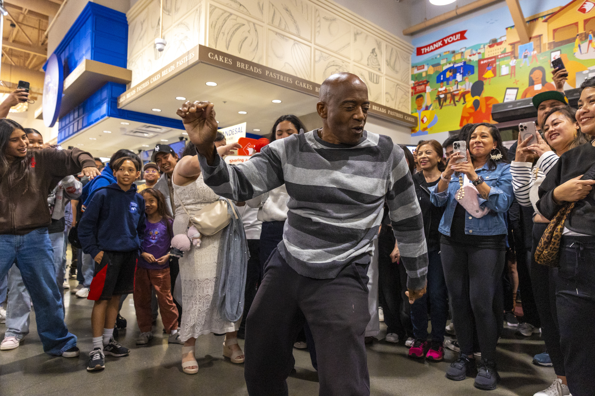 A Black party attendee dances in the middle of a circle that's formed in the middle of a supermarket.