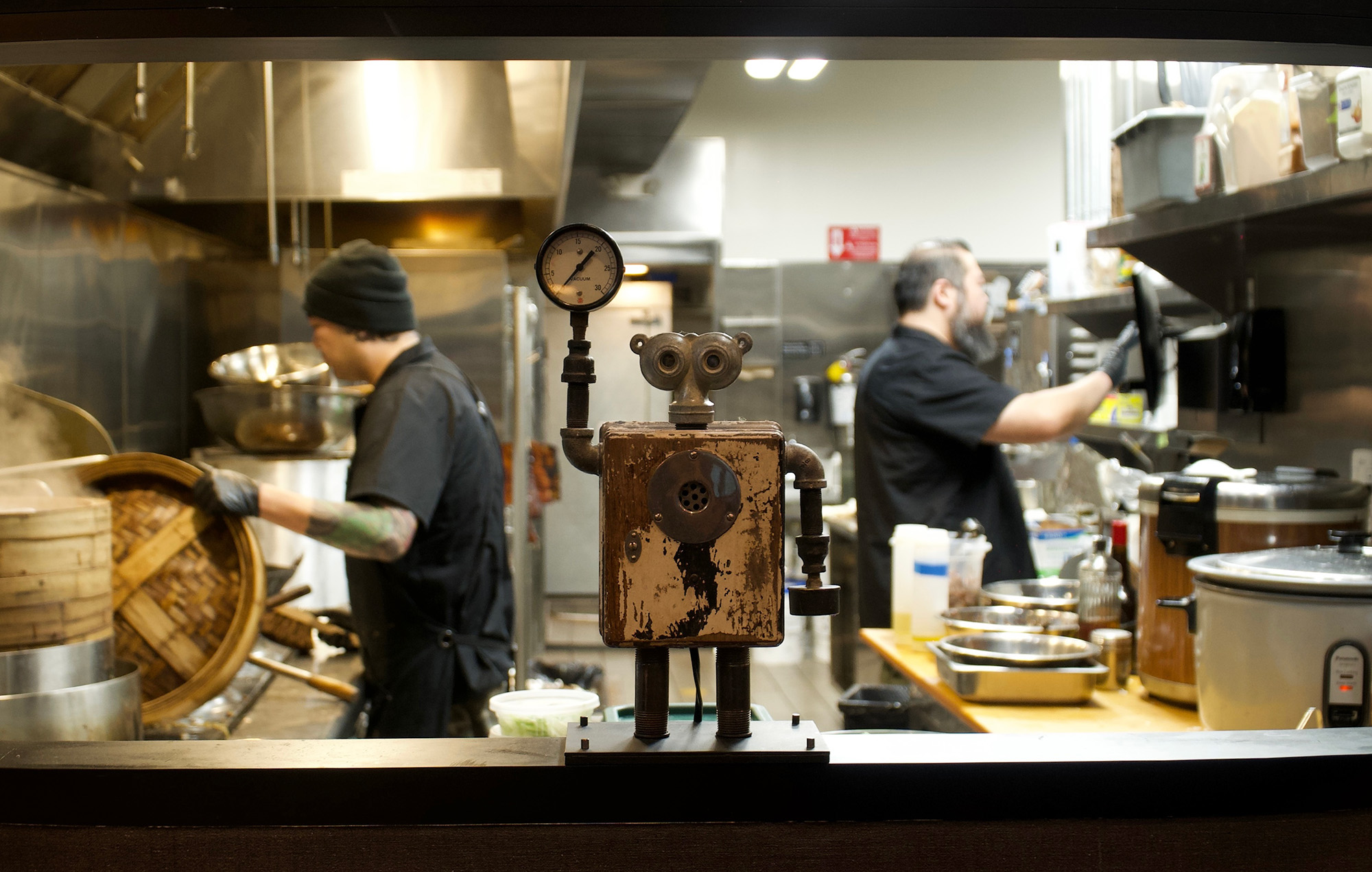Two chefs work in a busy Chinese restaurant kitchen.