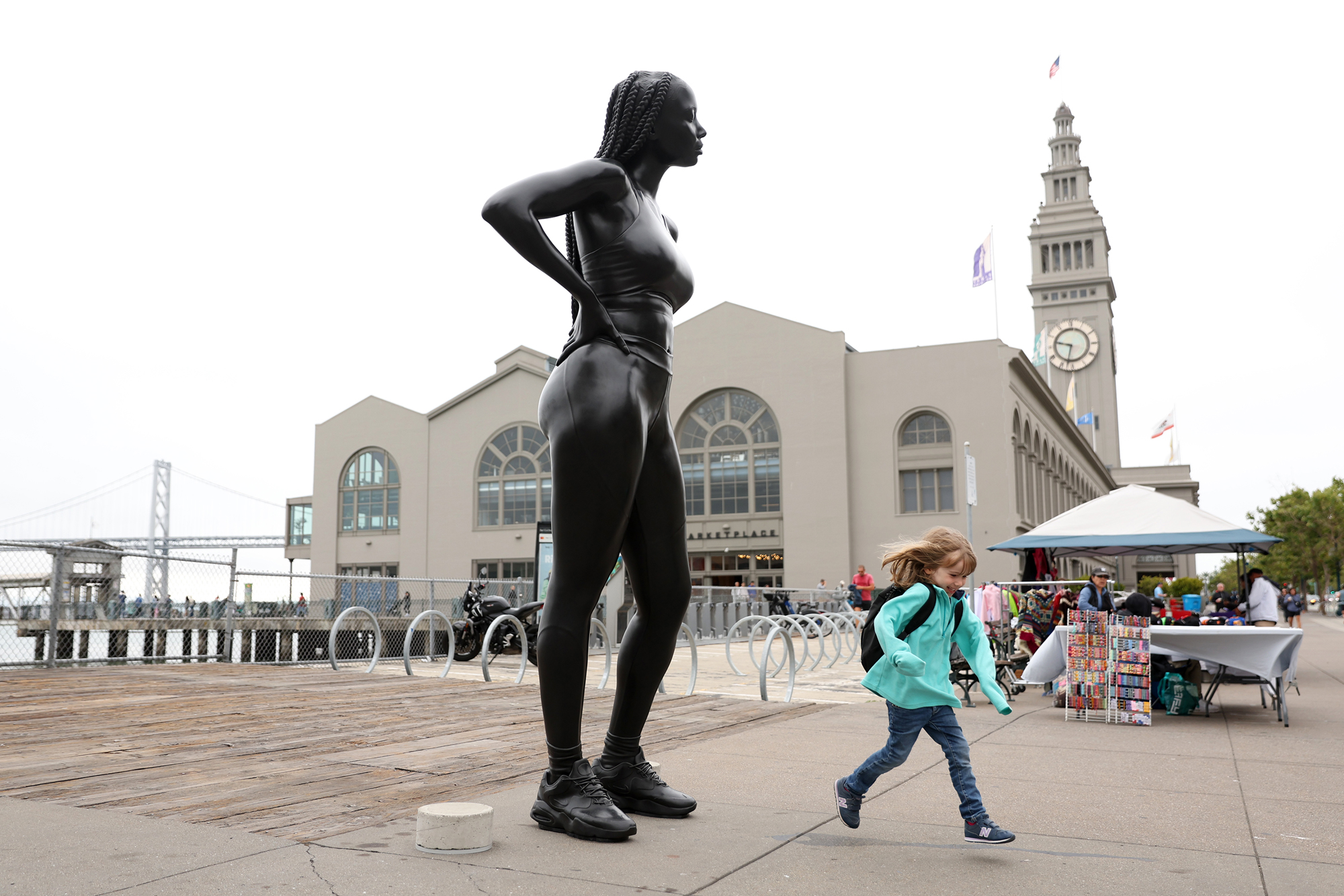large bronze of young woman in jogging gear in front of ferry building