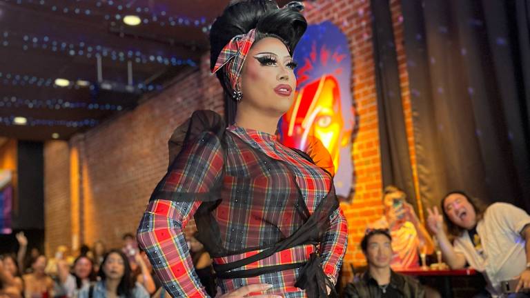 a Filipino-American drag queen in colorful clothes struts in front of an audience