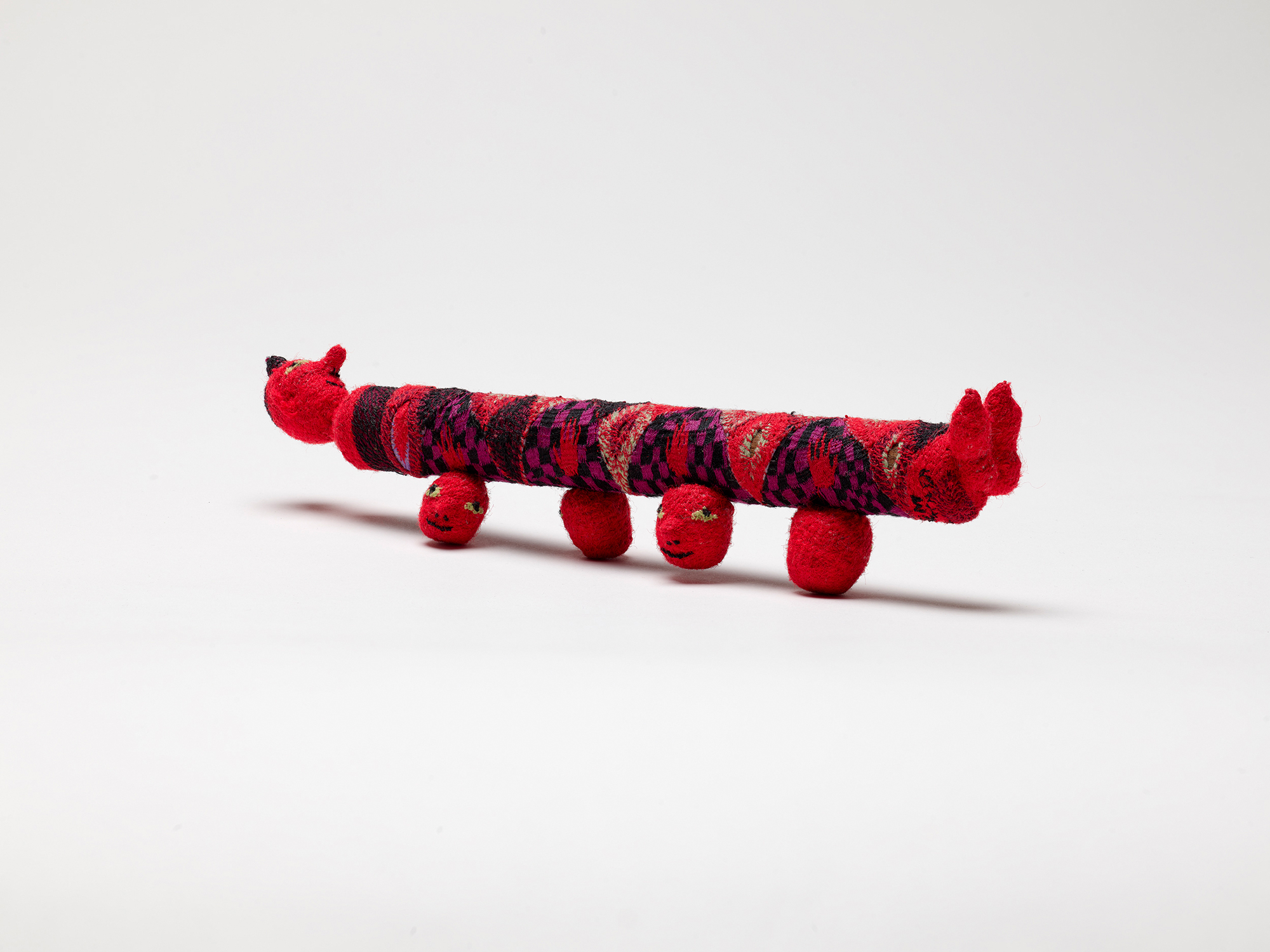 woven-covered long sculpture of cylindrical body with "head" legs