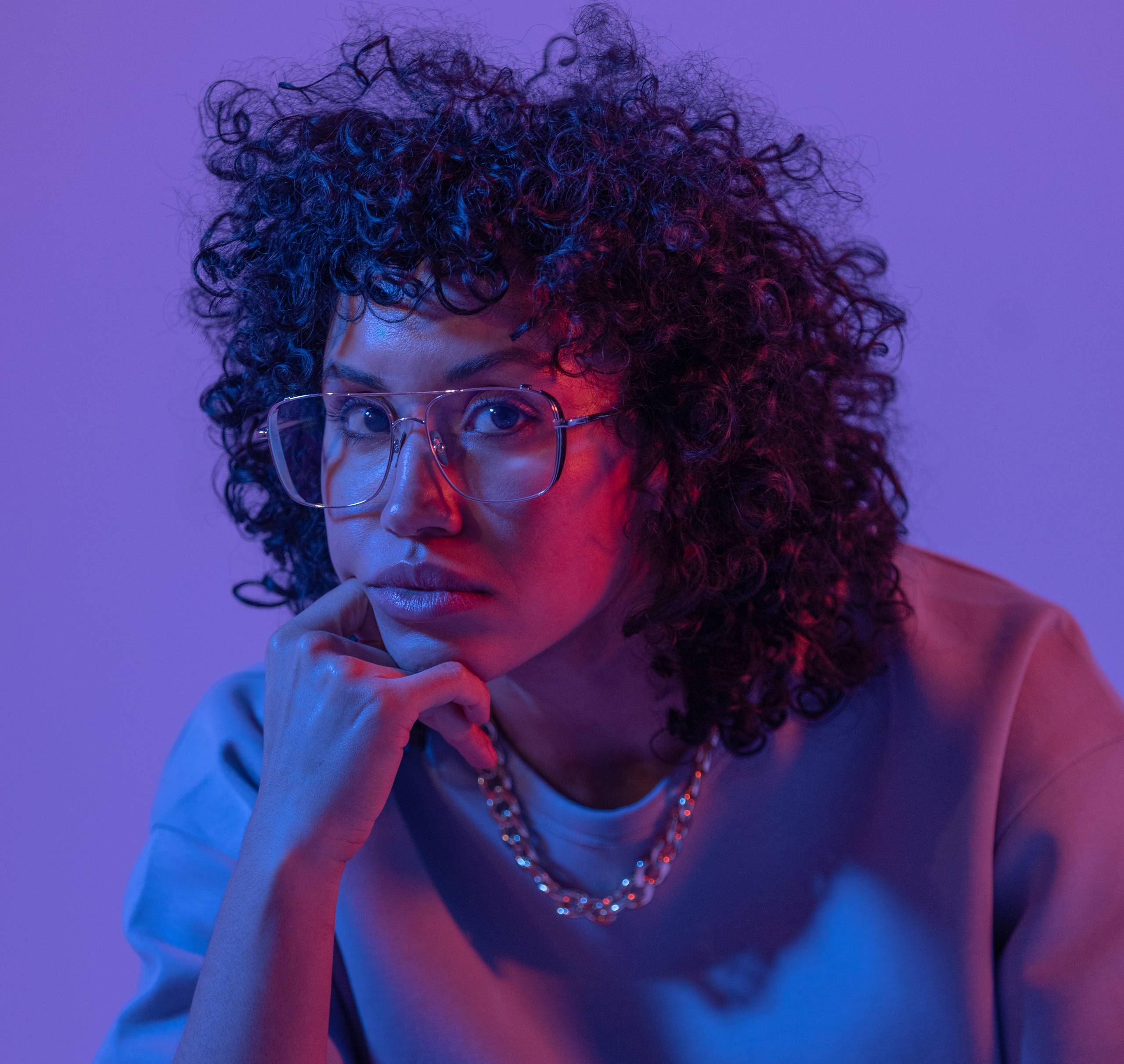 A singer poses in a studio with purple and blue lighting.