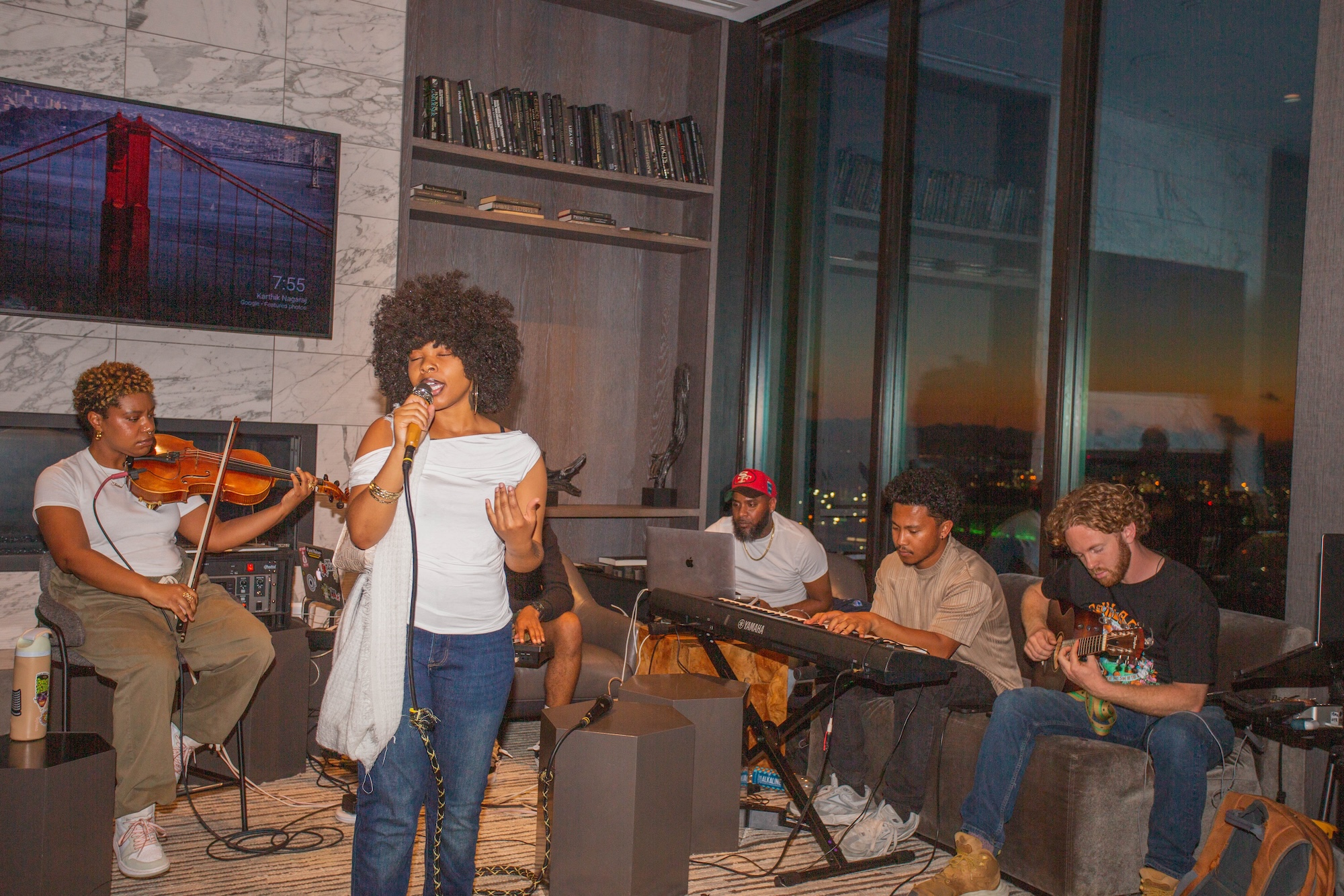 A woman with a big afro sings as she's backed by a band.