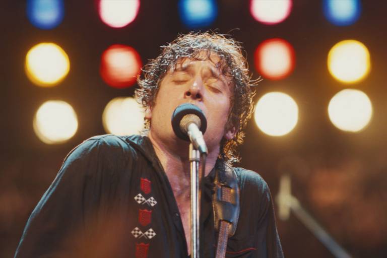 sweaty man sings into mic, eyes closed