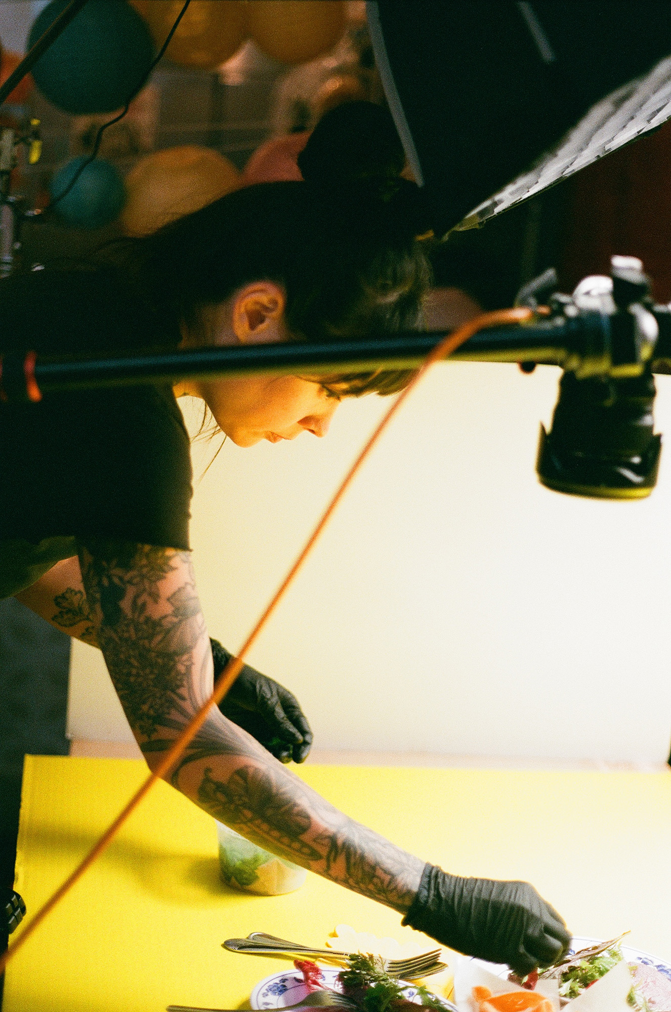 A behind-the-scenes image of a chef arranging a plate of food for a photo shoot.