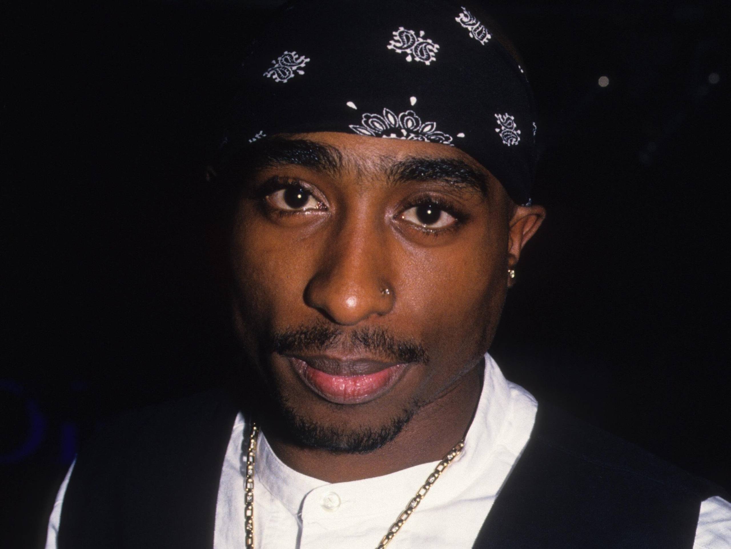 Close up photo of a young handsome Black man’s face. He is wearing a white shirt and a black bandana around his head.