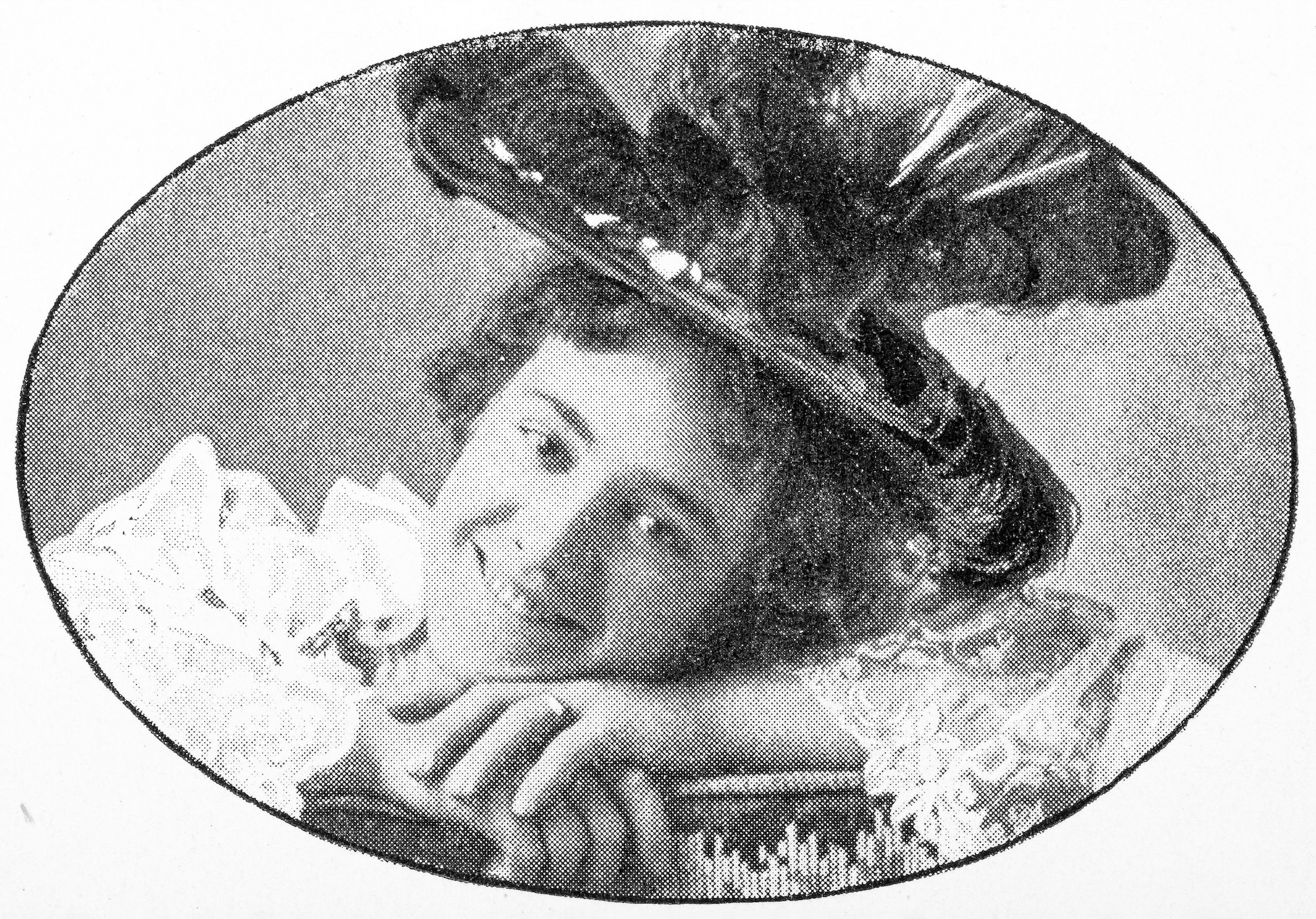An oval, grainy, black and white photograph of a white woman wearing a large elaborate hat and white shirt with lace cuffs. She is resting her chin on her folded hats and smiling broadly.