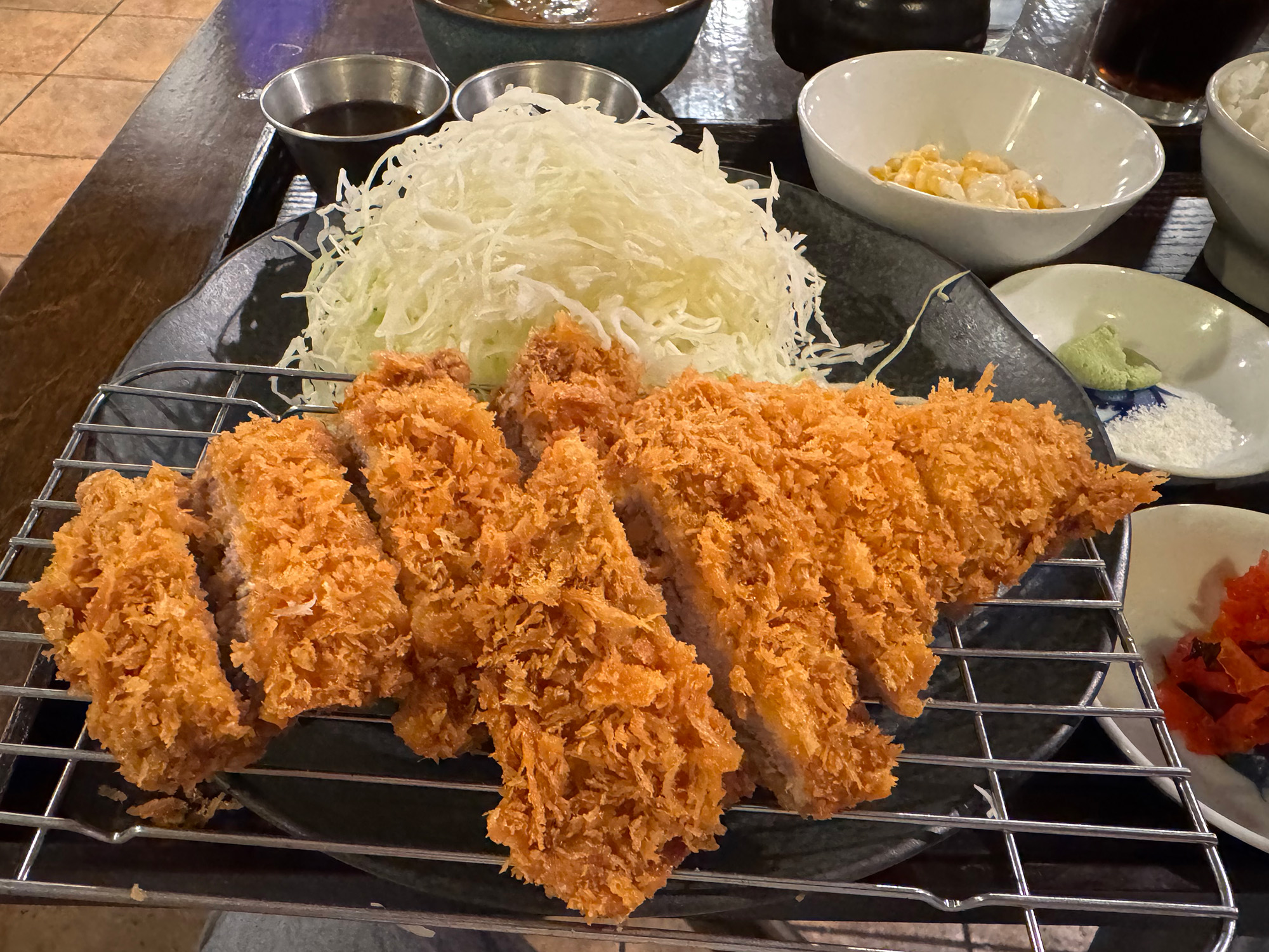 Fried pork cutlet served on a wire rack, with a pile of shredded cabbage on the side.