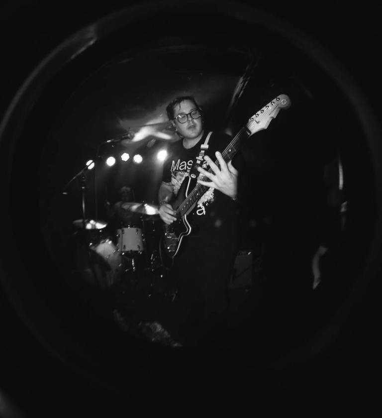 A black and white photo of a musician playing a guitar on stage.