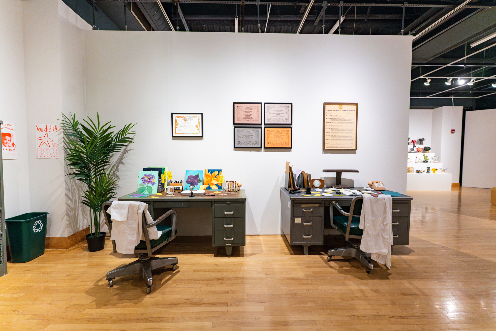 office set up in gallery space with fictional diplomas on wall