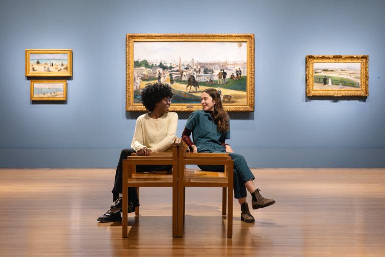 two people turn to face each other on museum bench in front of Impressionist paintings
