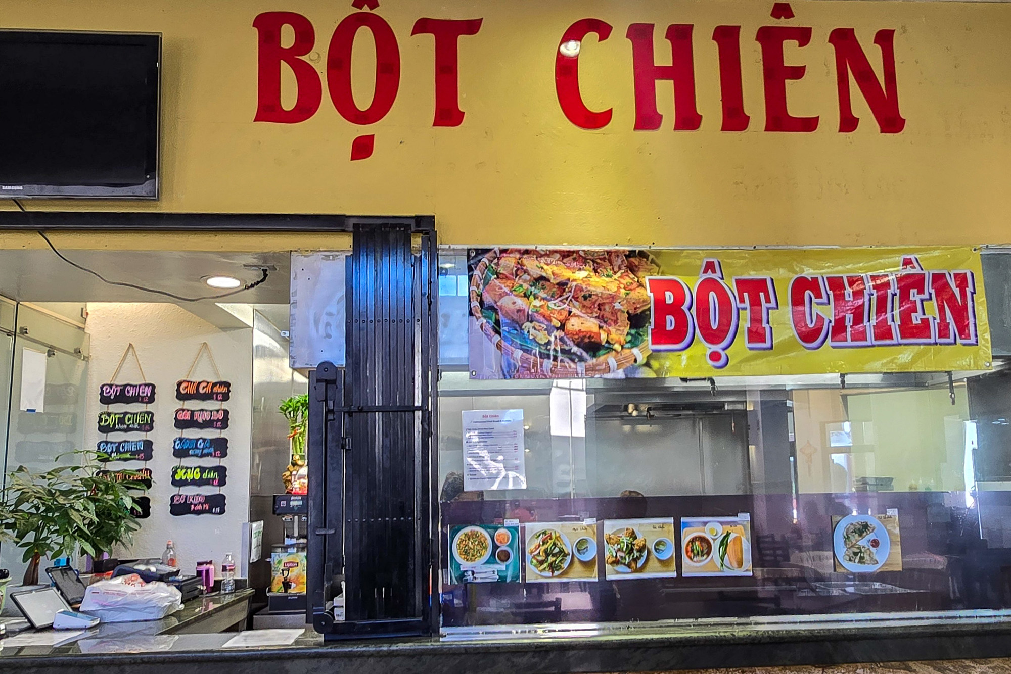 Exterior of a food court kiosk. A yellow banner overhead reads, "Bột Chiên."