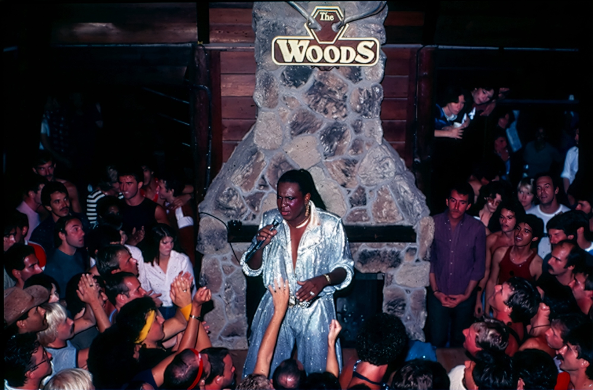 A vintage photo of a disco star performing in front of a crowd of young, gay fans.