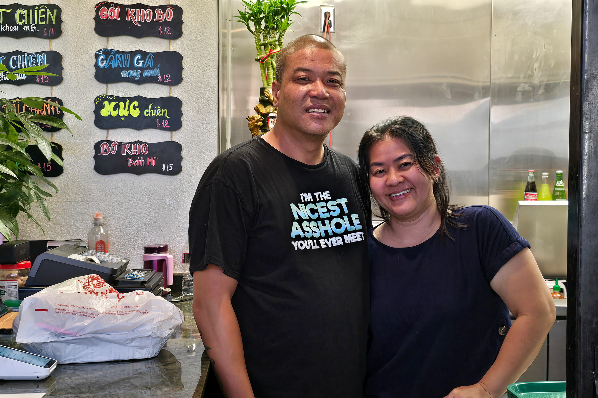 Asian American man and woman pose for a portrait. The man's black T-shirt reads, "I'm the Nicest Asshole You'll Ever Meet."