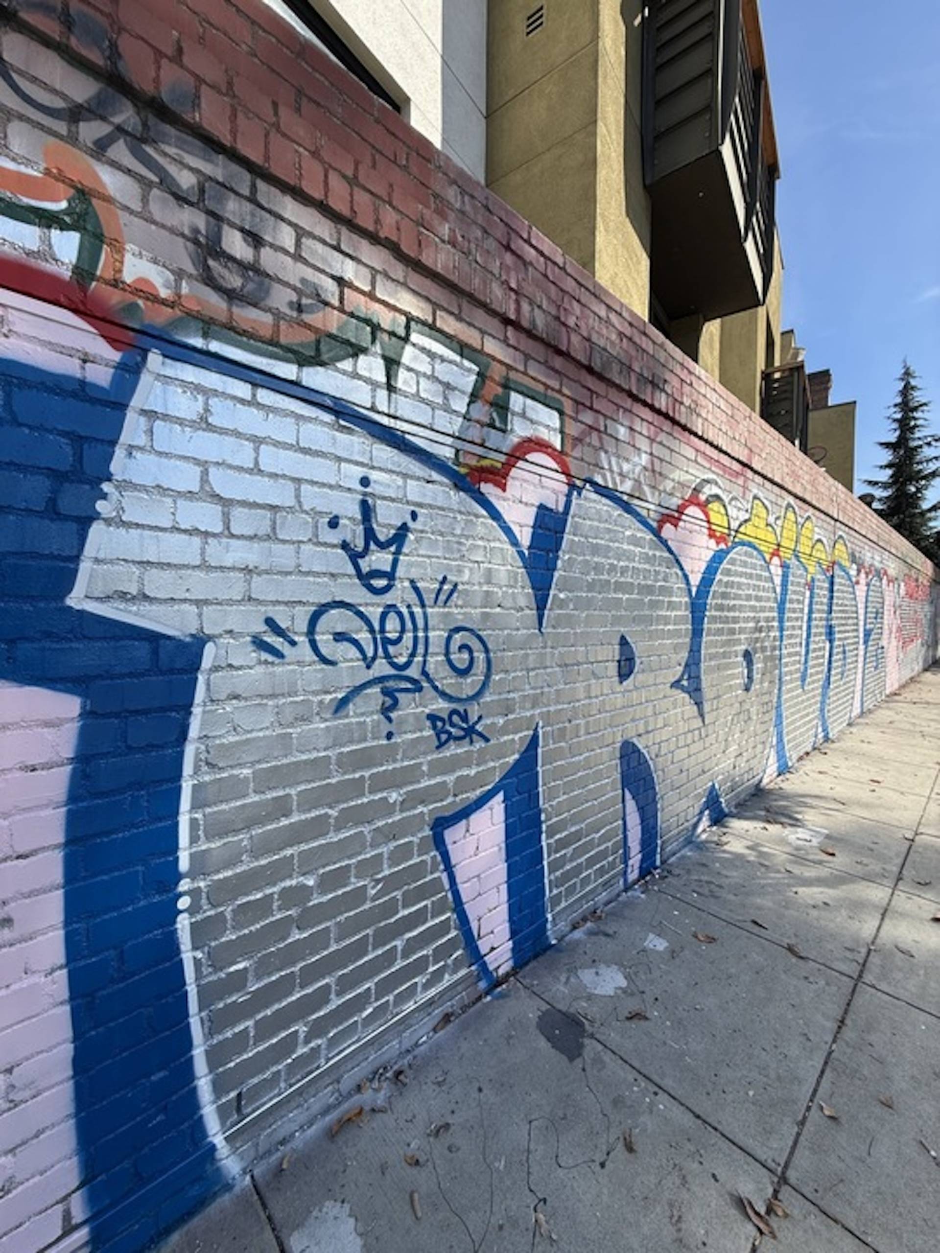 A close up image of a mural that reads "PROUD," painted in metallic silver and royal blue.