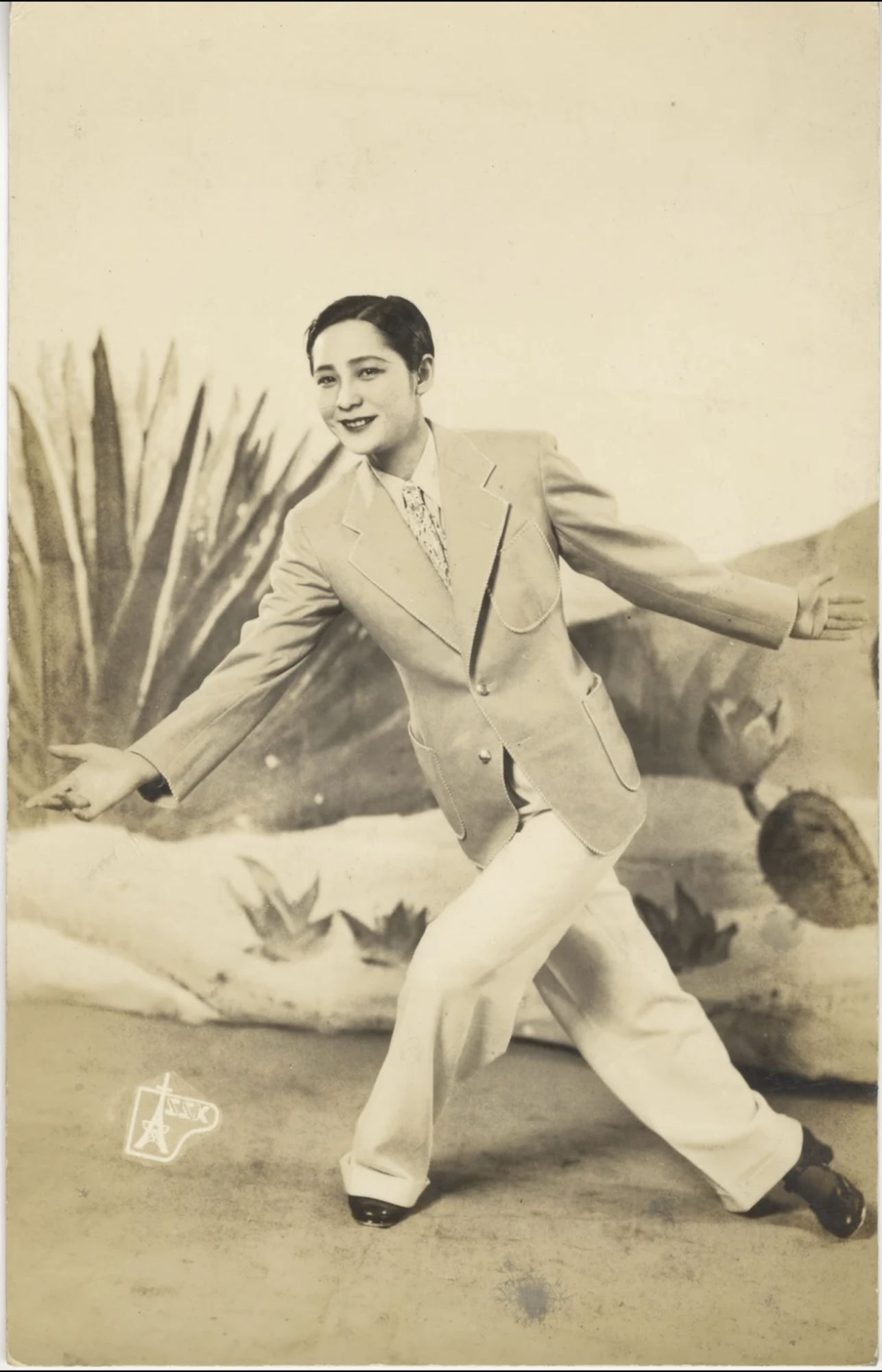 A woman dressed in a man's suit, hair slicked back in a masculine style.