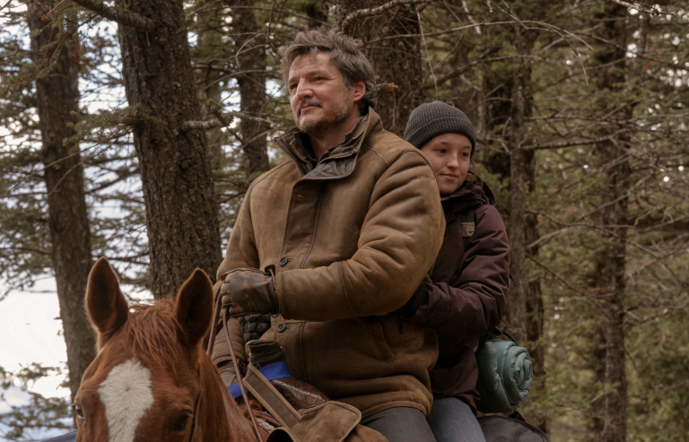 A middle aged man with greying hair sits atop a brown horse in the forest. Seated behind him is a teenage girl. They are both dressed in warm clothing.