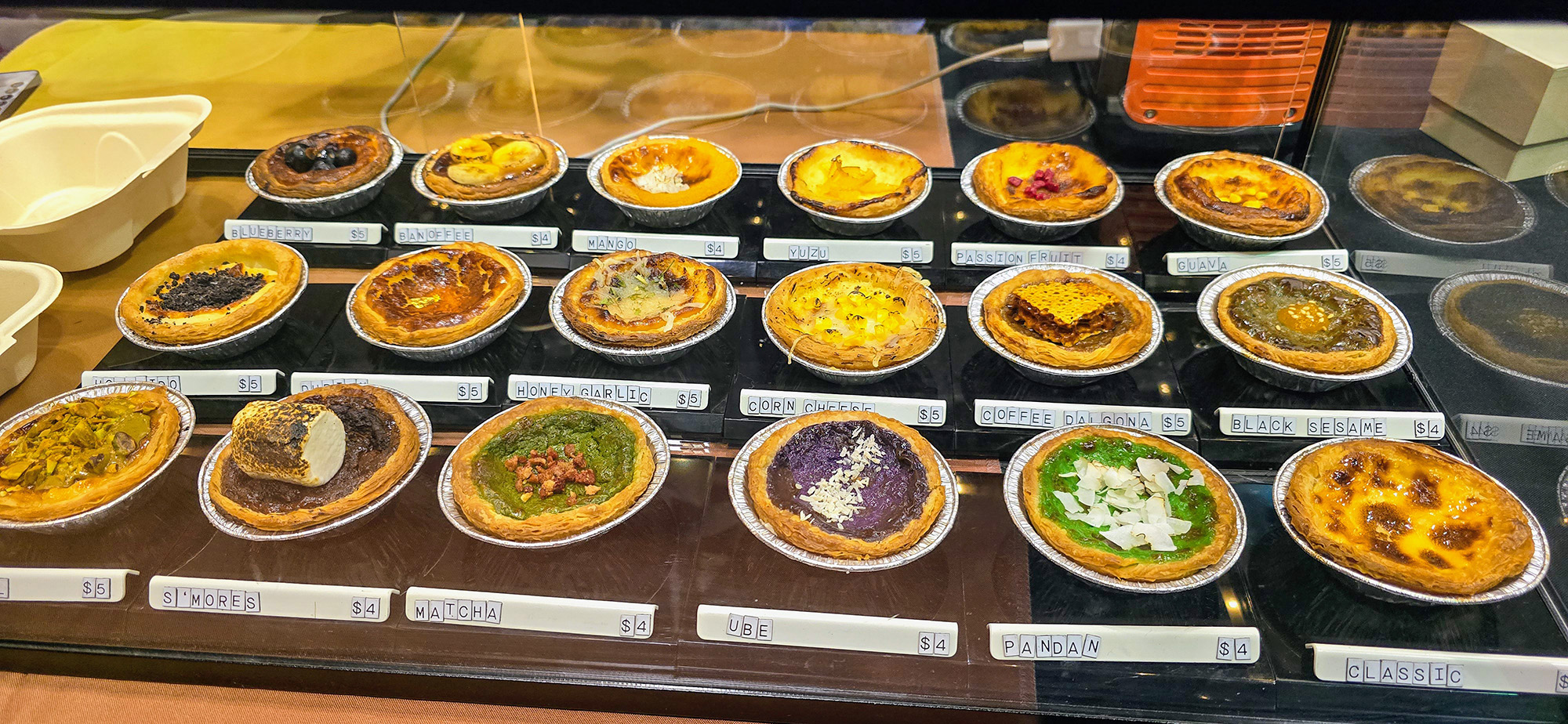 Display case with 18 different varieties of egg tarts.