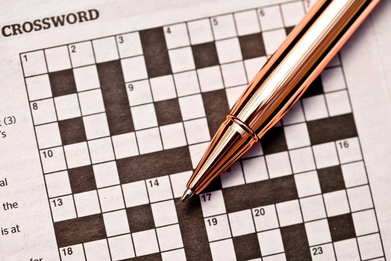 A pen placed on top of an empty crossword puzzle.