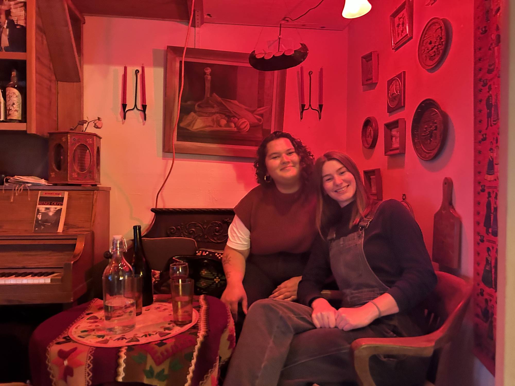 two people pose for a photo in a dimly-lit bar.