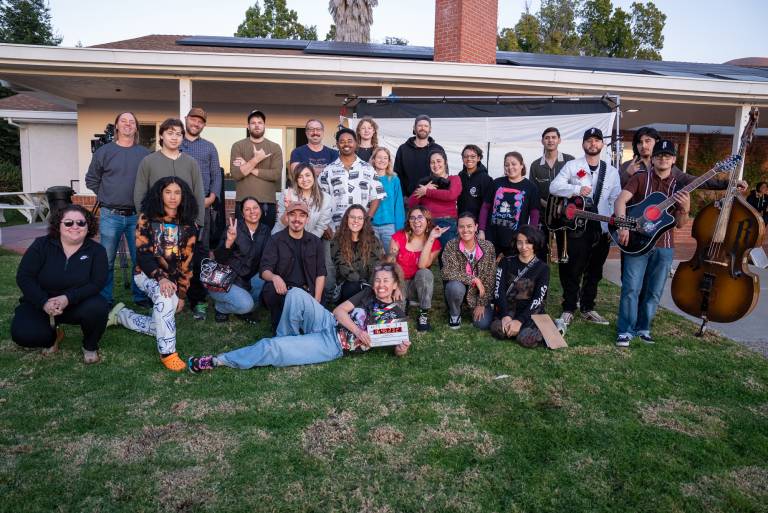 over a dozen people pose in the front yard of a residential building