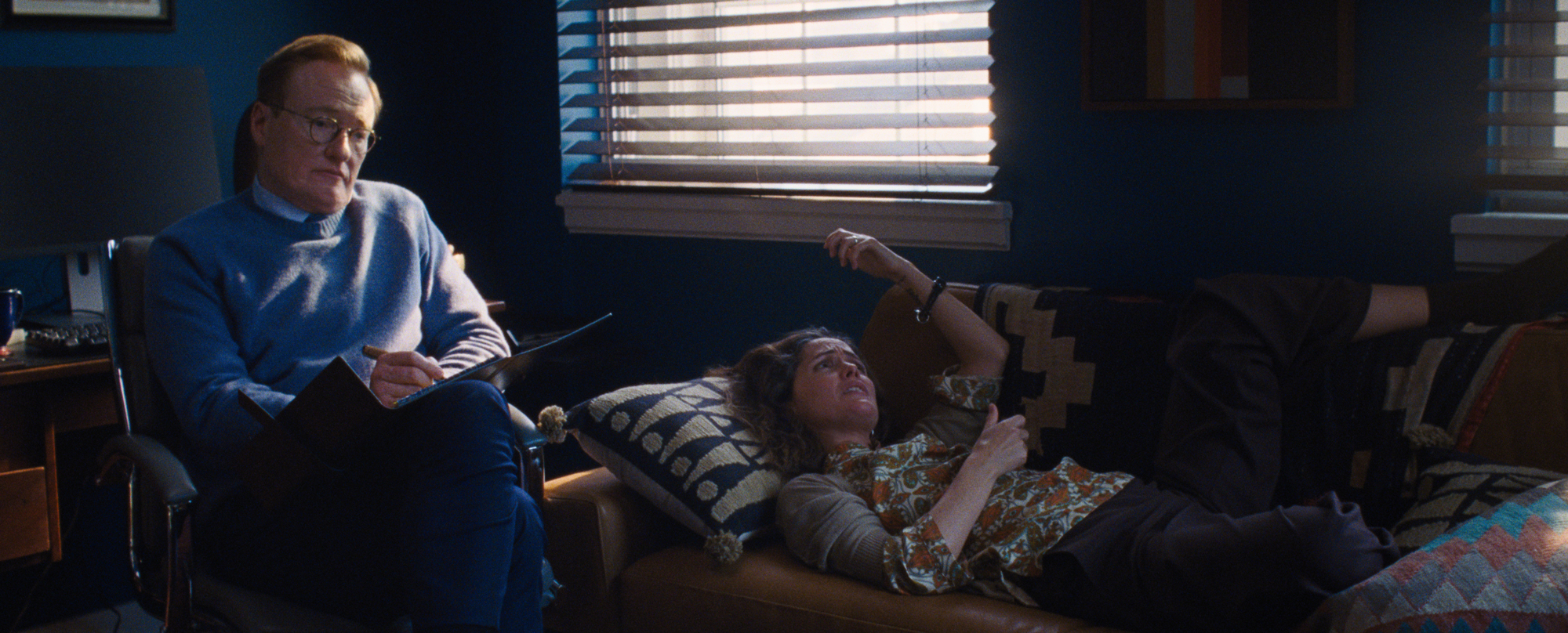 woman on therapist couch, man taking notes beside her