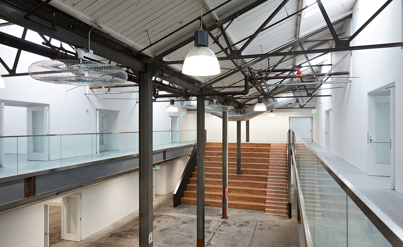 atrium with 2nd-level walkway and wooden stairs at back of space