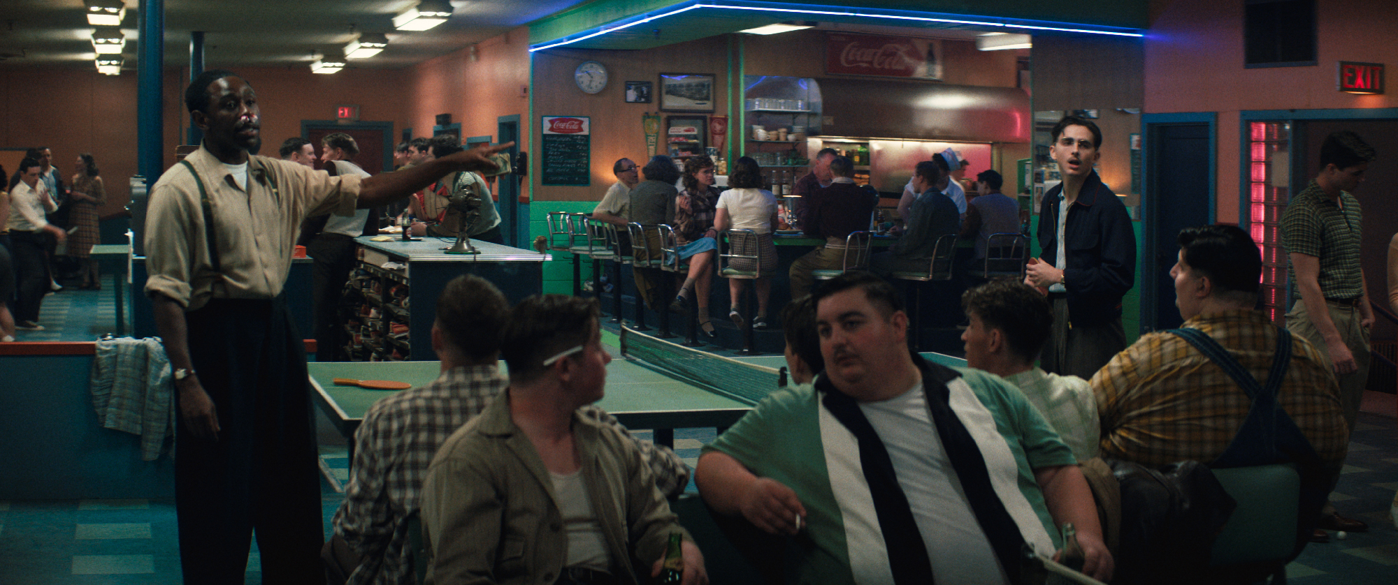 black man and white man gesture over ping pong table in bowling alley