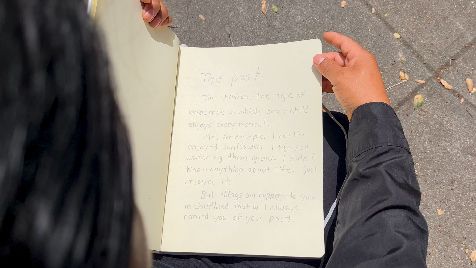 person holds notebook page with handwriting on it