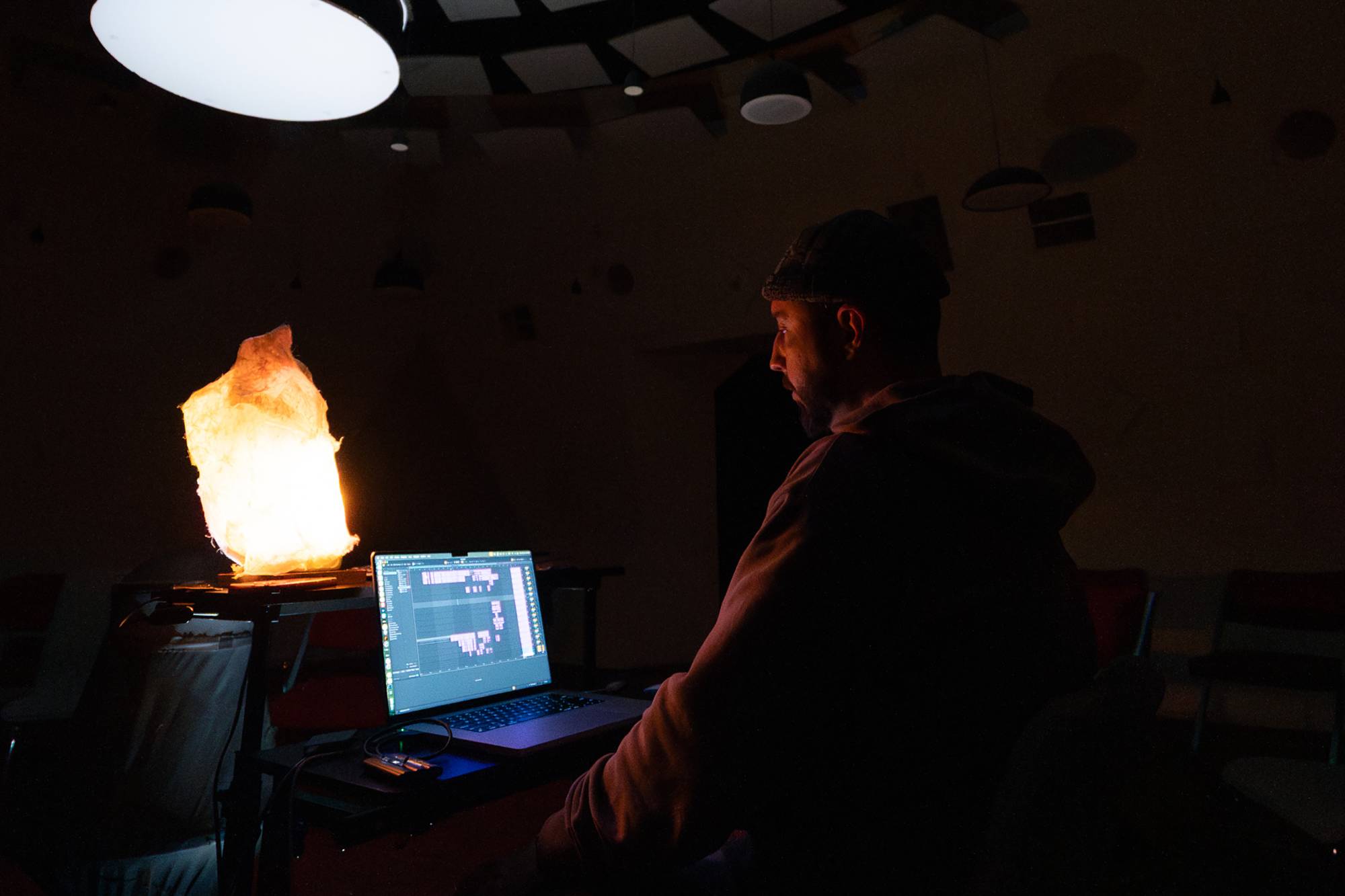 A man in the dark at a laptop, the screen glow of which shines on his figure