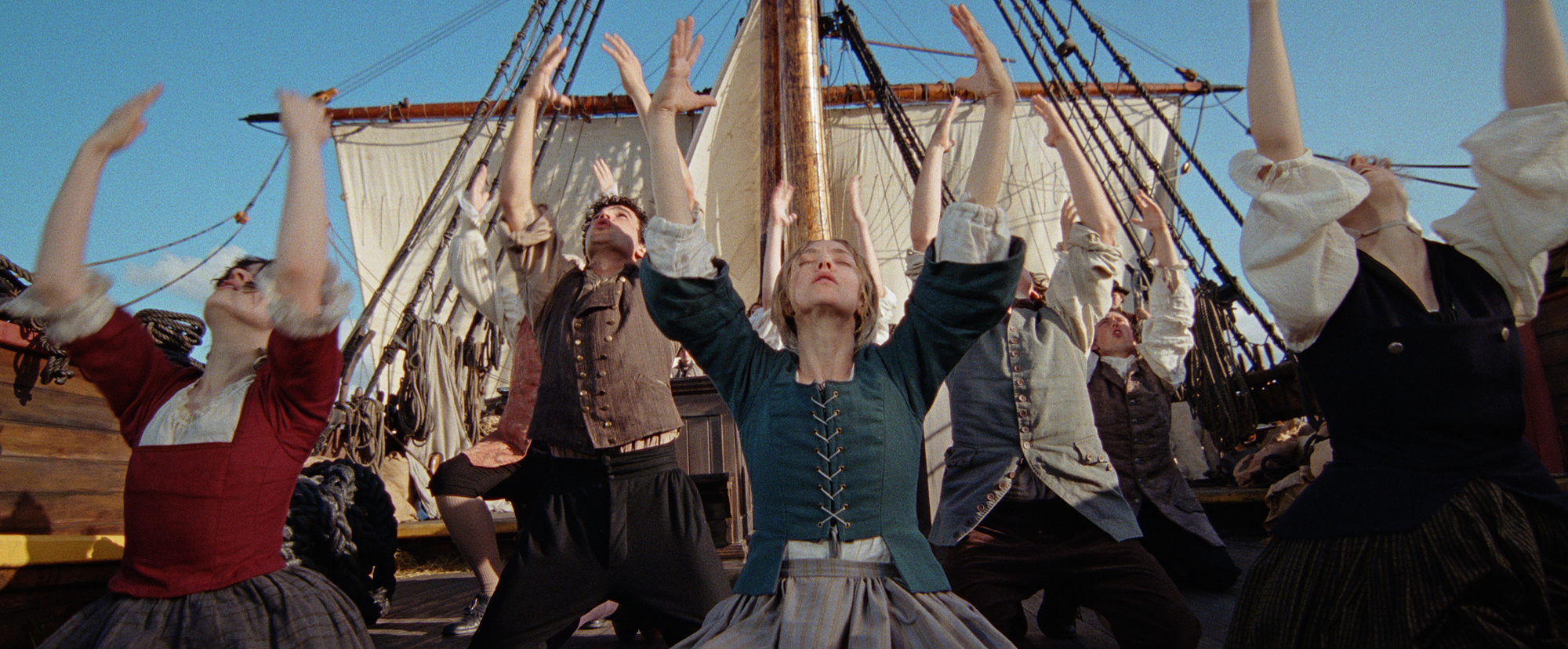 people in 18th-century clothes raise arms together on ship deck