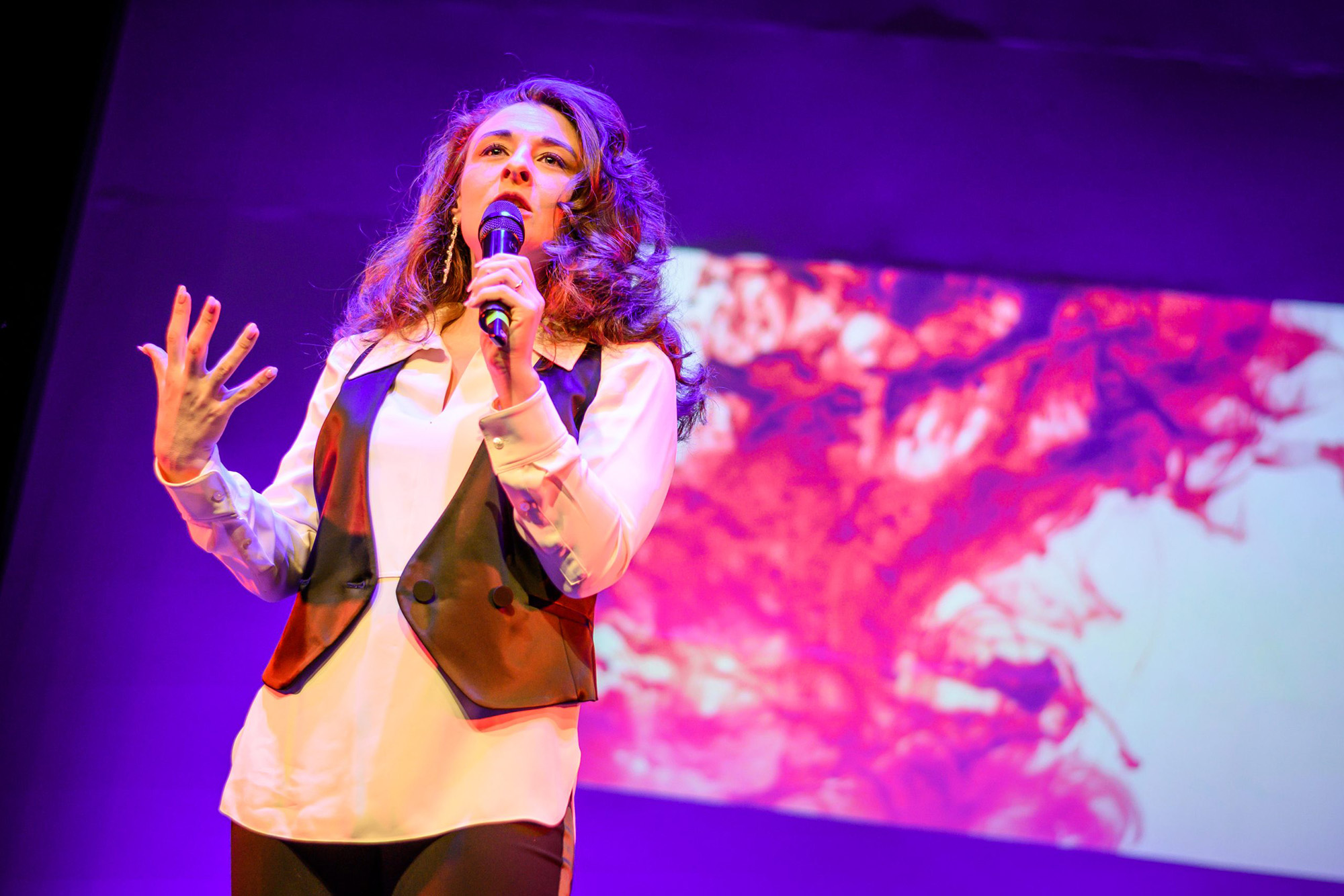 A woman holding a microphone as she speaks on stage.