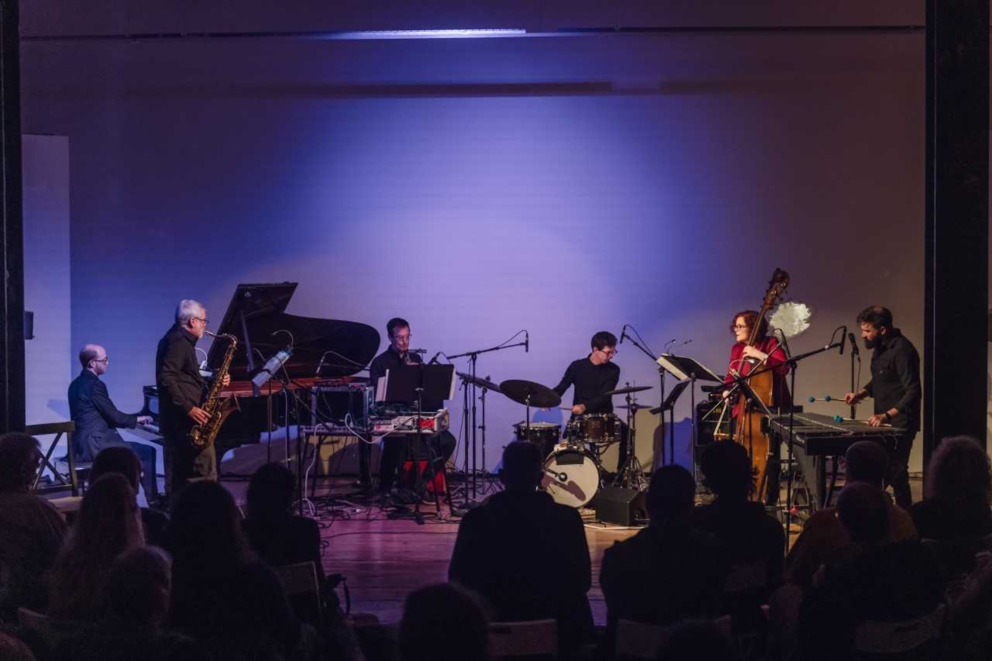 A group of people stand on stage playing jazz together.