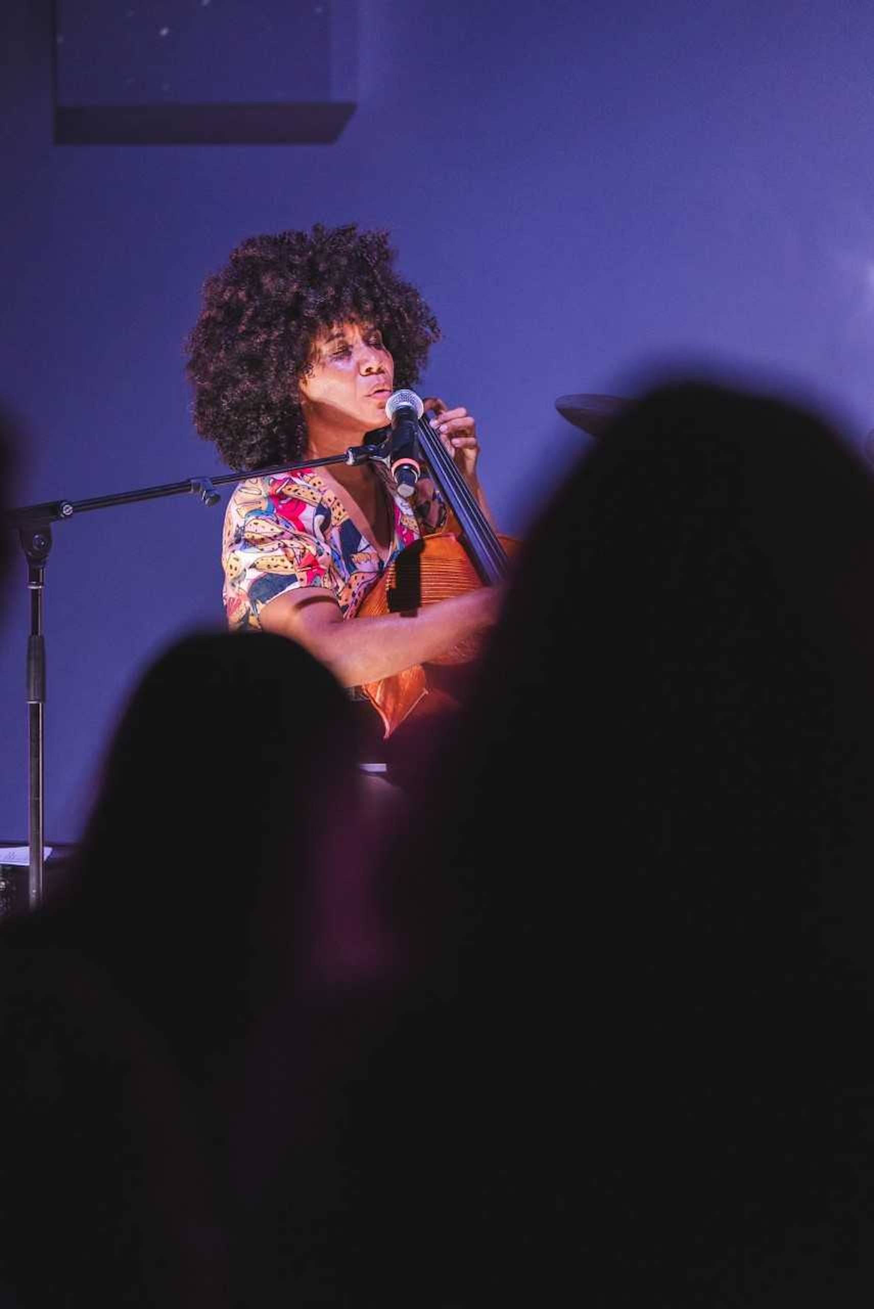 A woman with an afro sings while on stage.