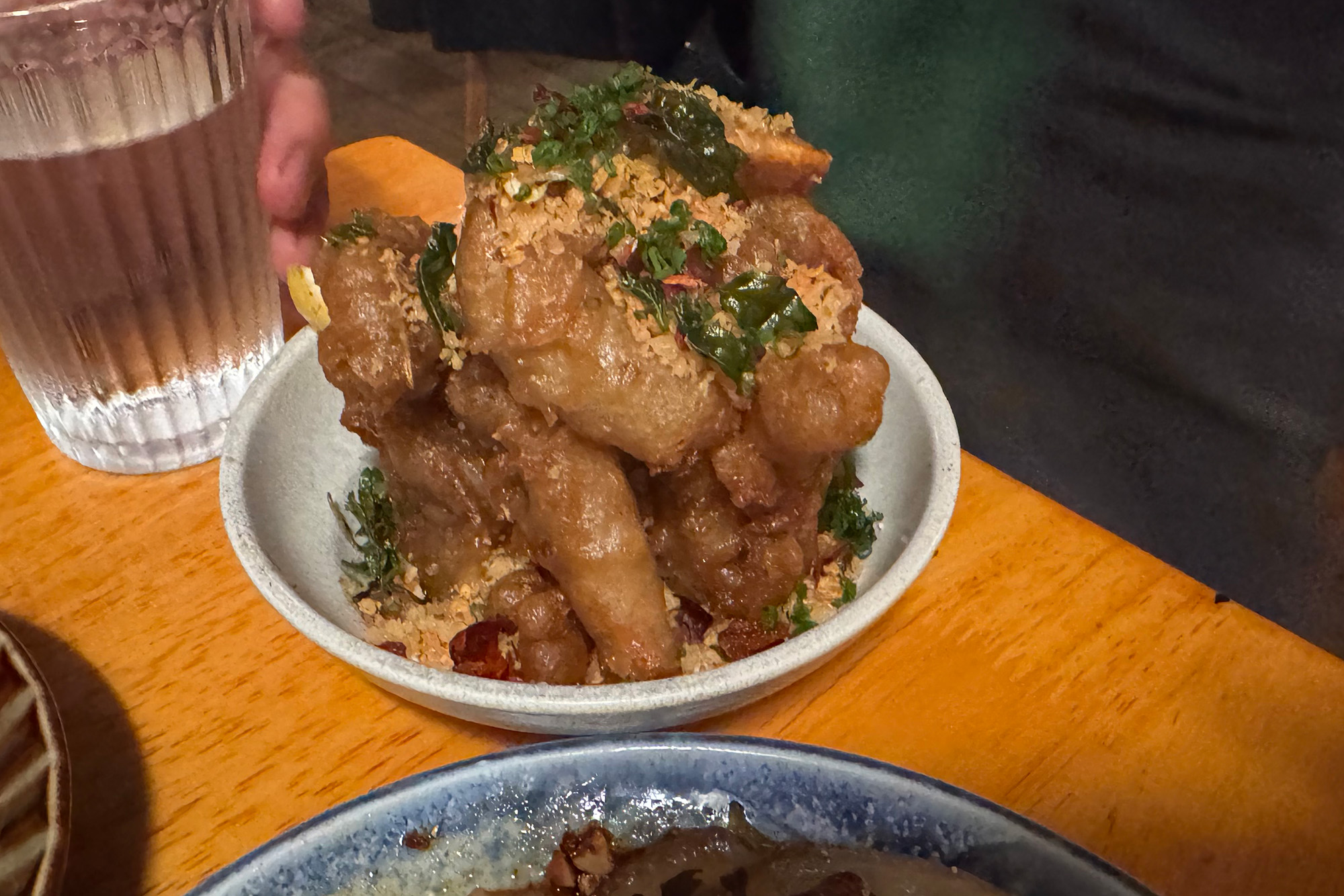 A bowl of fried soft-shell crab covered with bits of fried garlic and jalapeño.