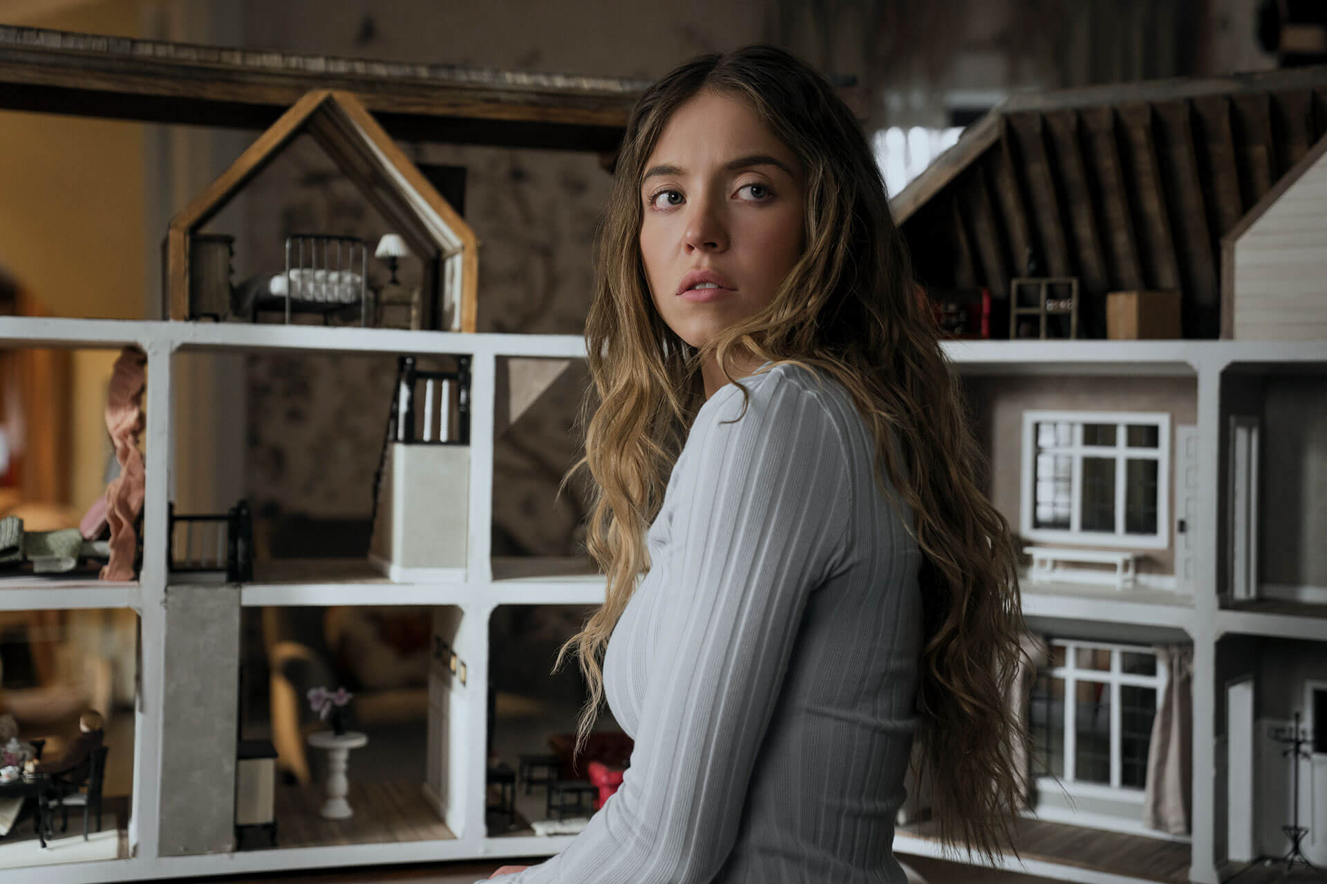 A woman stands in front of bookshelves.
