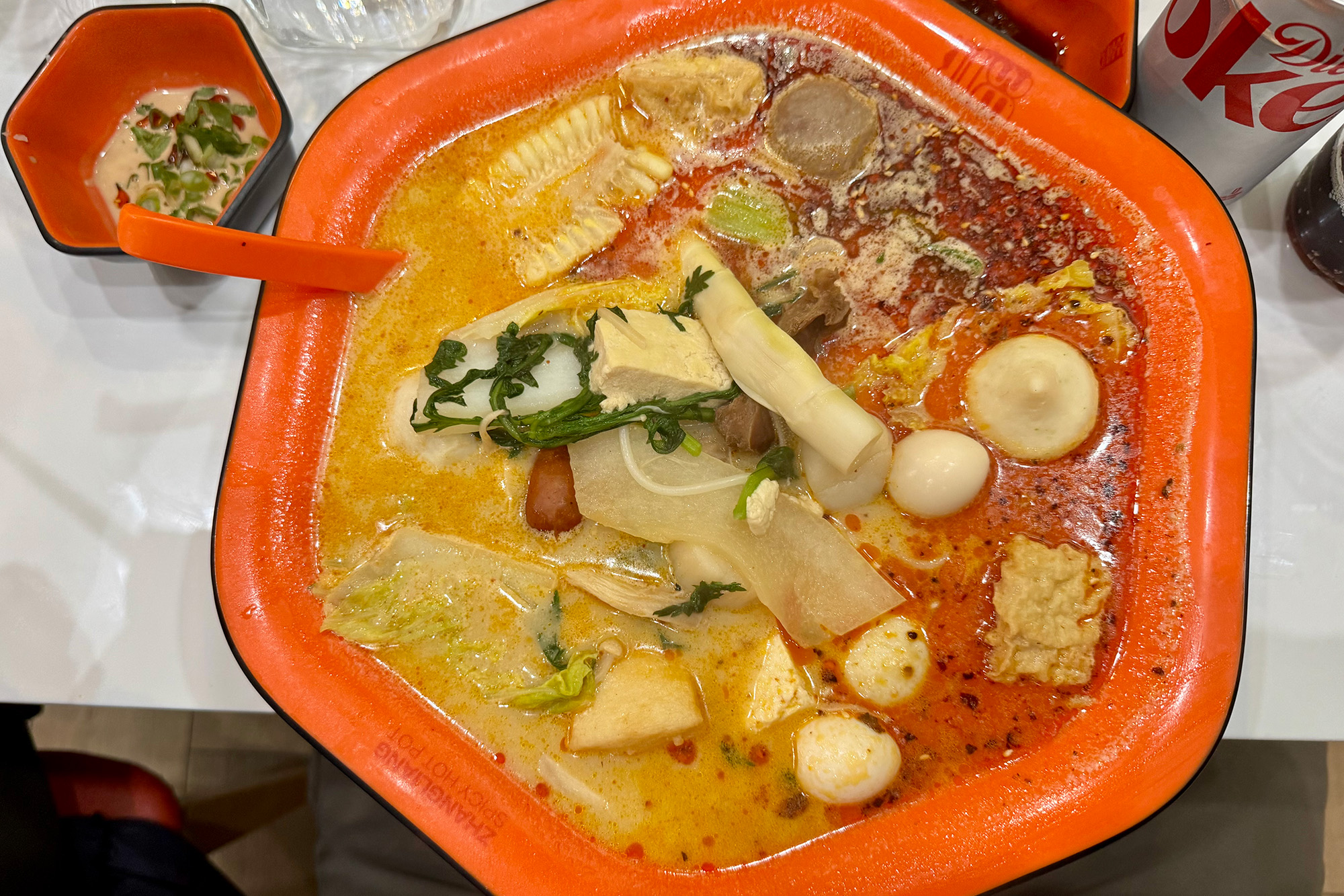 Large bowl of one-person malatang-style hot pot, with fishballs, meat and quail eggs.