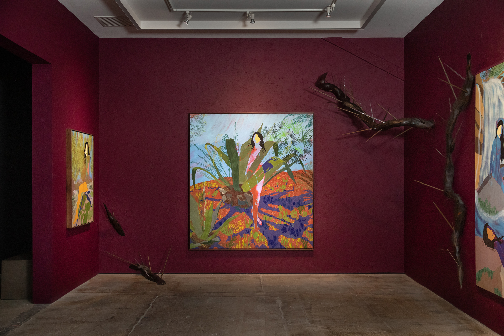 large paining of woman in landscape with wooden sculptures surrounding