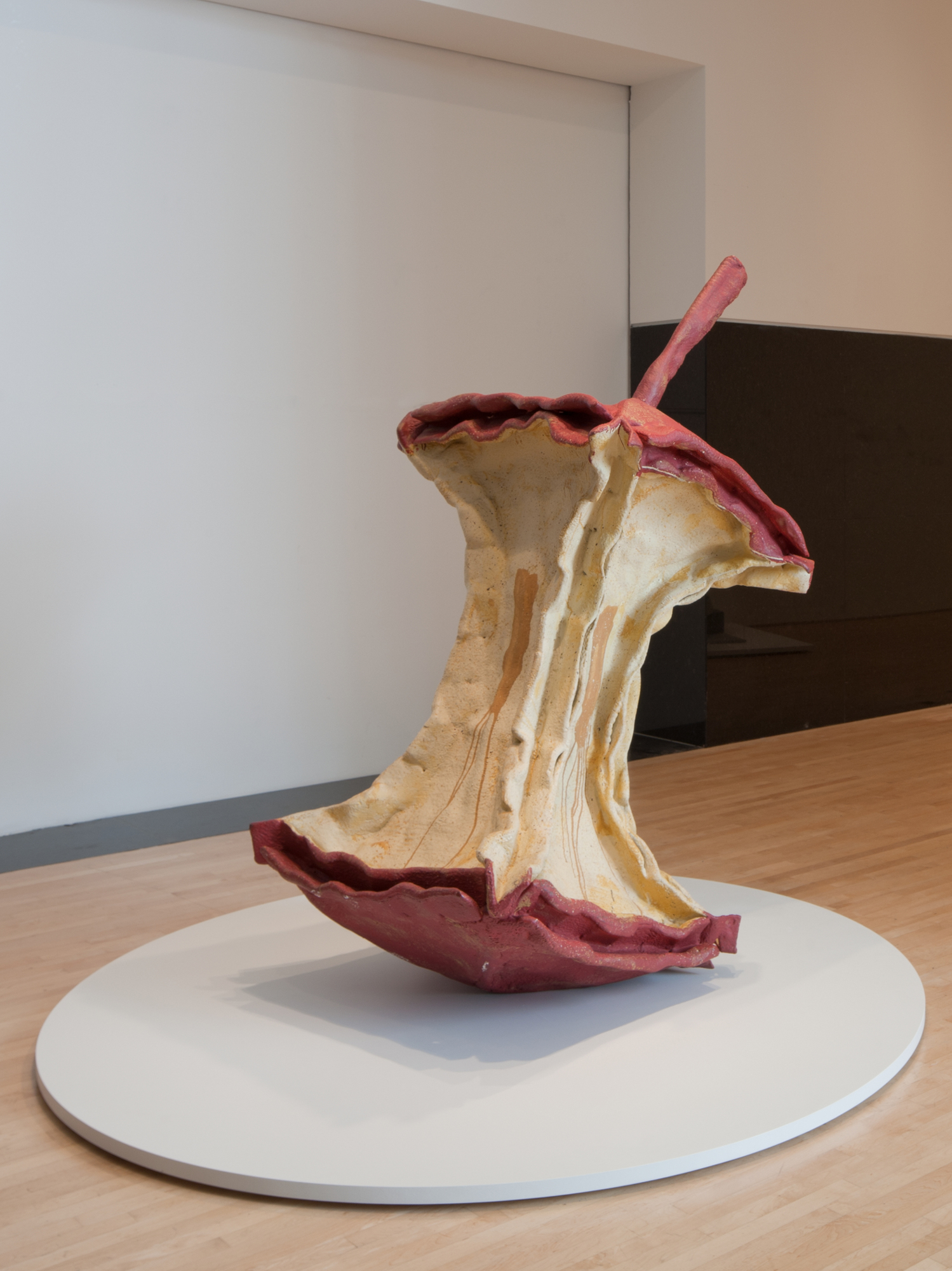sculpture of apple core tilted on round pedestal