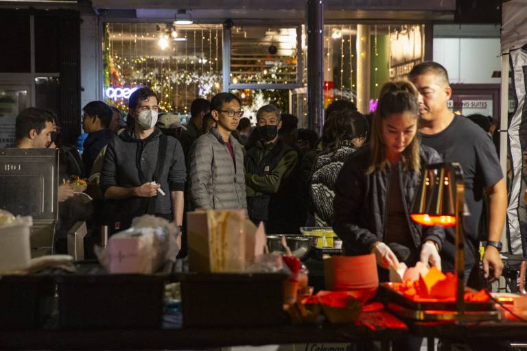 A crowd of customers waiting in line at a night market food stand.