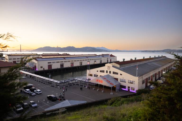 view of two long pier buildings with Marin Headlands and Golden Gate bridge in background